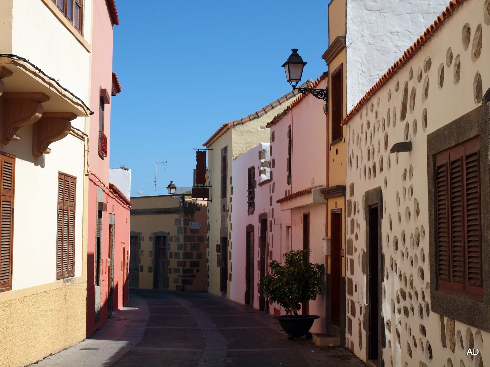 The charming narrow streets of Aguimes Old Town showcase the island's distinctive colonial architecture with pastel-colored buildings and traditional wooden details.