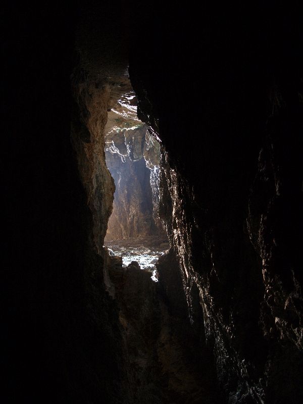 Light streams through the cave opening at Ajuy Caves, revealing dramatic basalt rock formations and the Atlantic Ocean beyond.