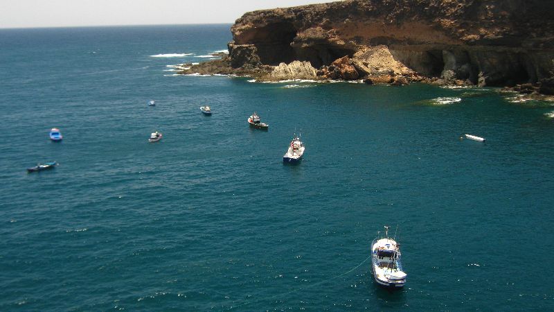 Boats anchor in the sheltered turquoise waters below the dramatic coastal cliffs and cave formations at Ajuy.