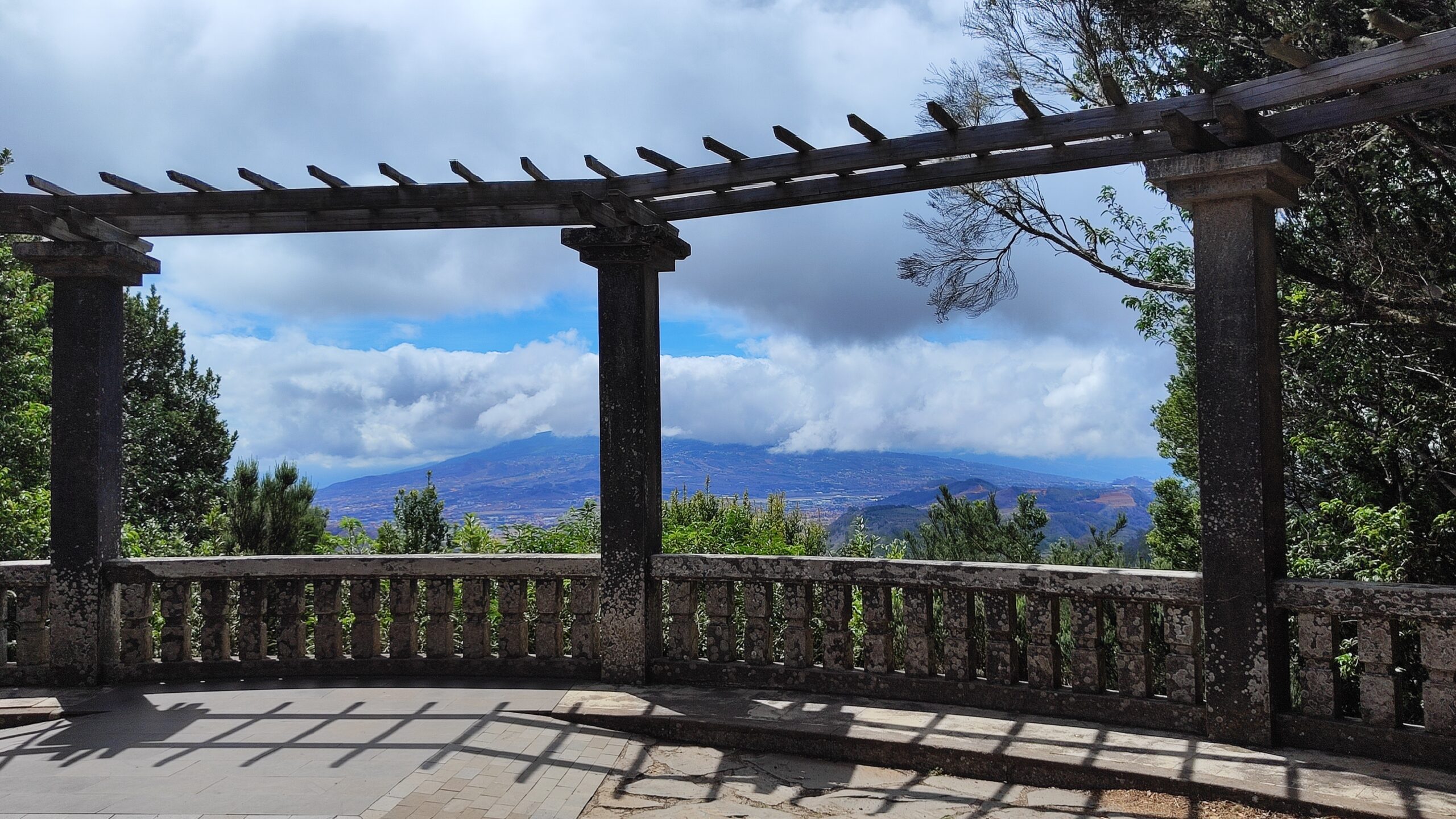 A shaded stone pergola provides sweeping views across the Anaga landscape toward the volcanic peaks in the distance.