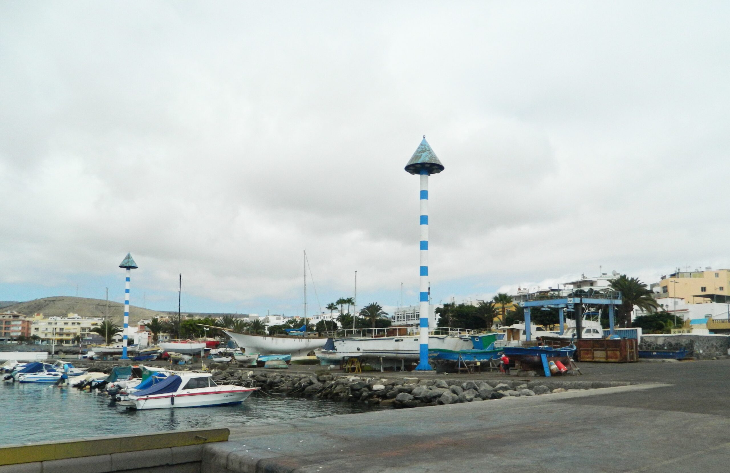 The distinctive striped lighthouse marks Arguineguín Harbor, a working port on Gran Canaria’s southern coast.