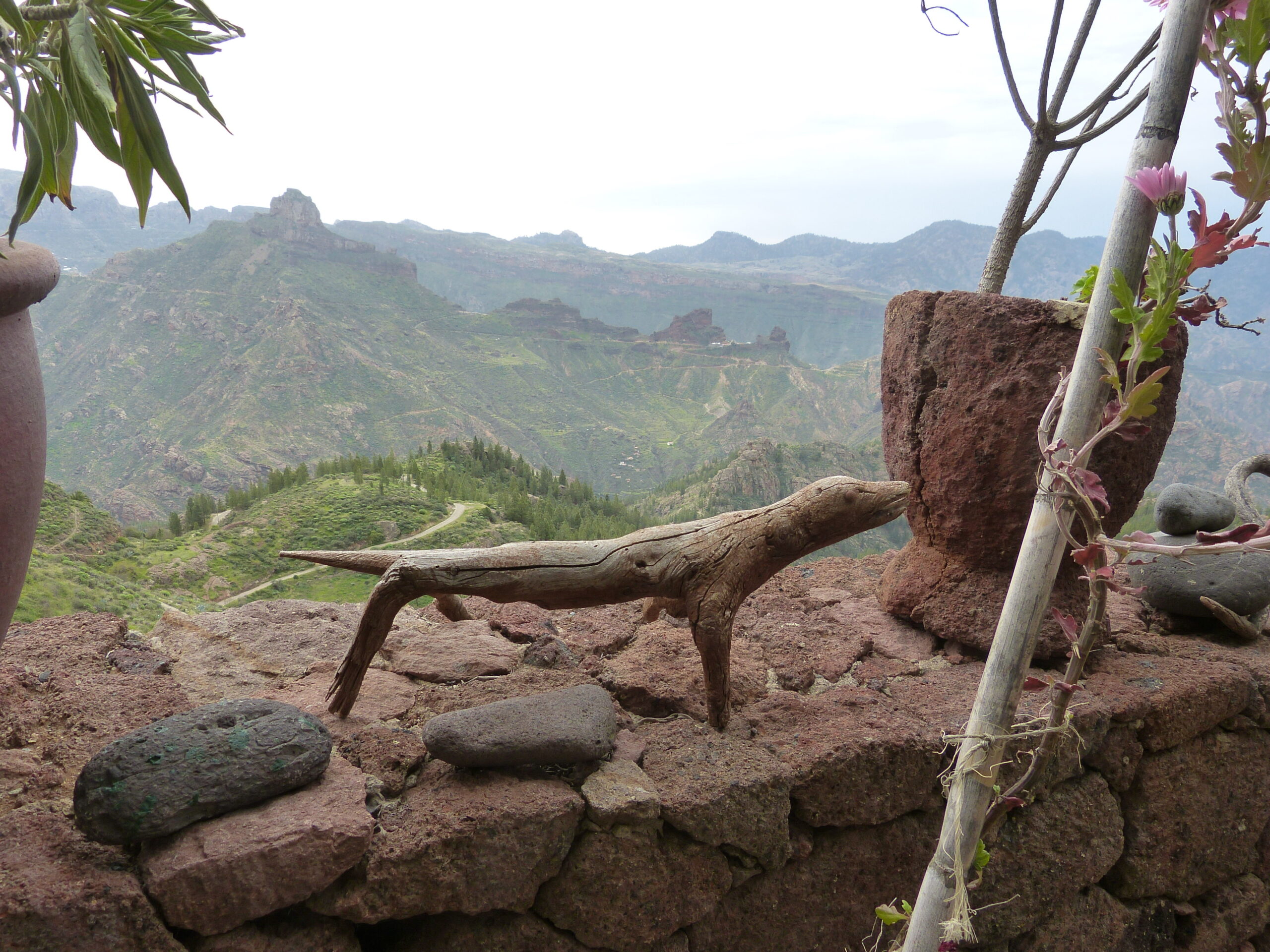 The dramatic volcanic terrain surrounding Artenara Caves, with layered mountain ridges and native vegetation framing the elevated vantage point.