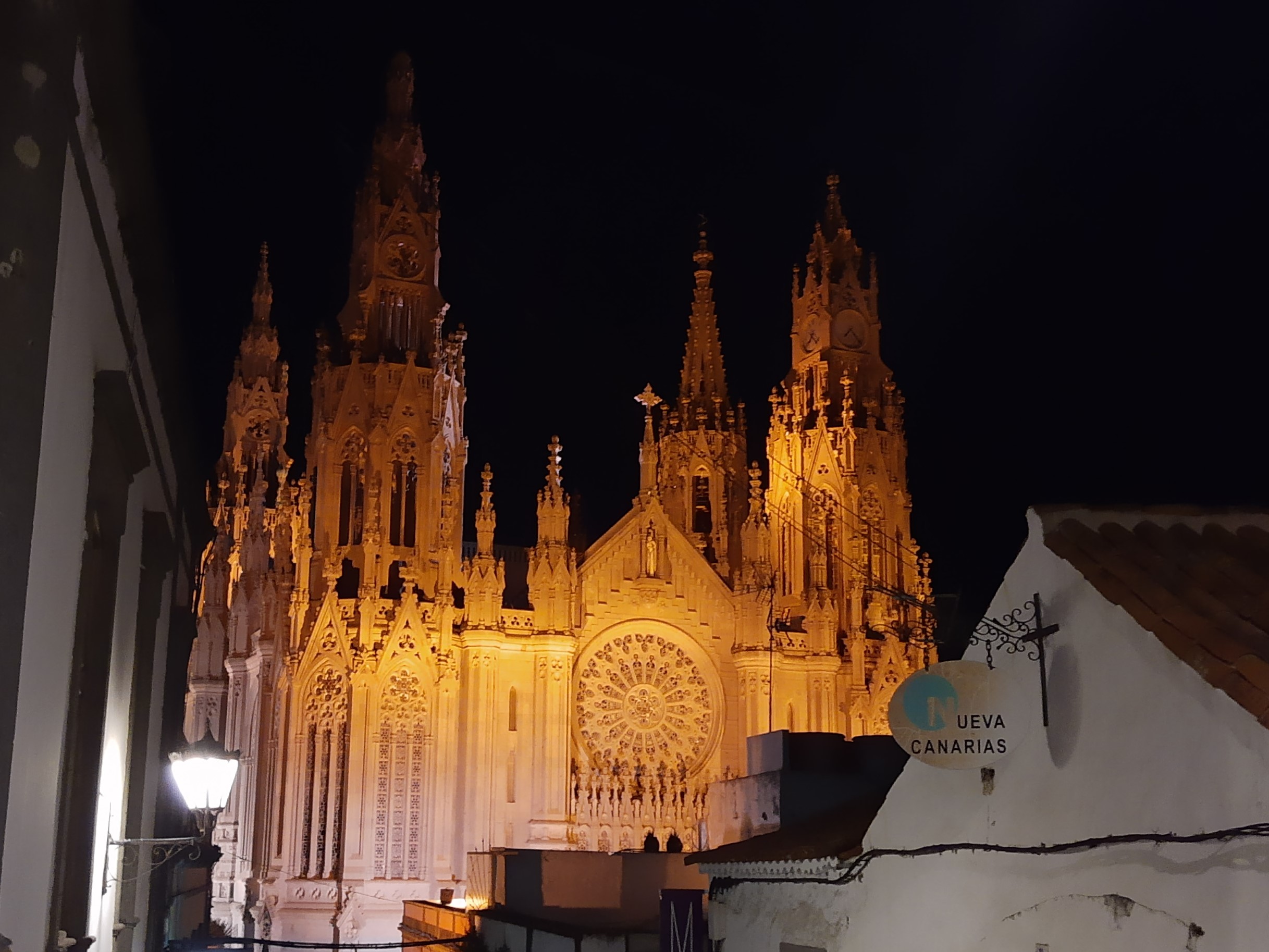Arucas Cathedral, dramatically lit in golden light against the night sky, showcases the Neo-Gothic architecture that dominates the town's main square.
