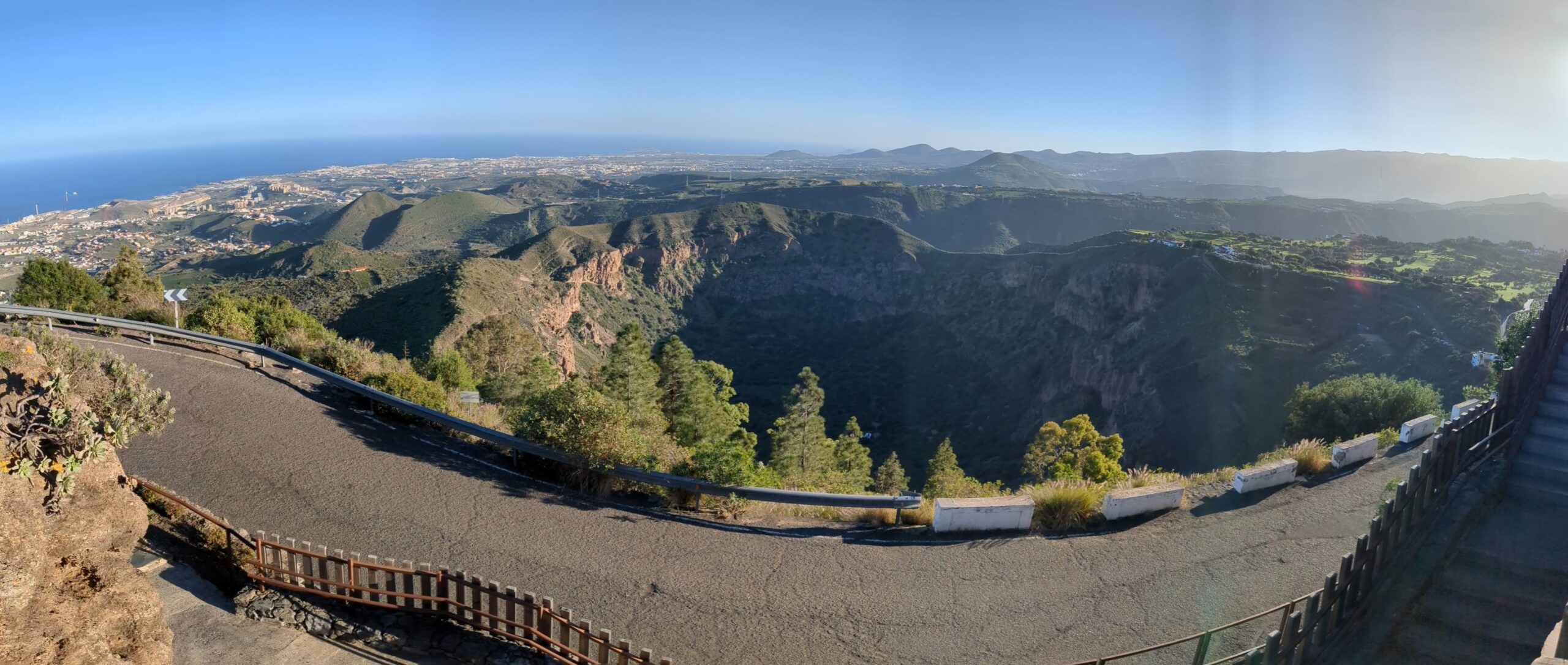 The Bandama crater reveals its dramatic volcanic geology, with lush vegetation in the caldera and expansive views across the island toward the coast.