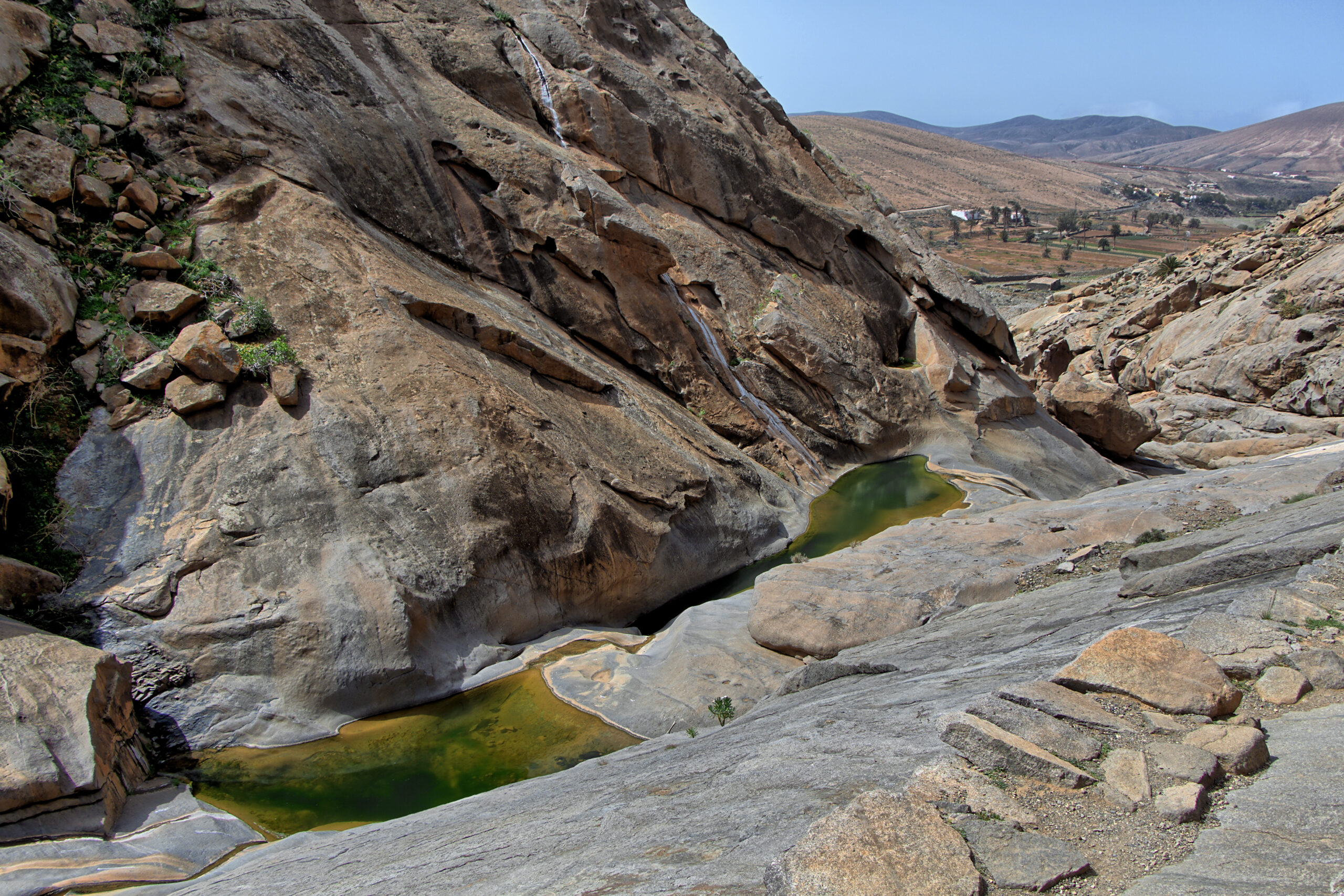 Barranco de las Peñitas showcases dramatic eroded rock formations and mineral-rich pools that create striking green hues in this remote Fuerteventura canyon.