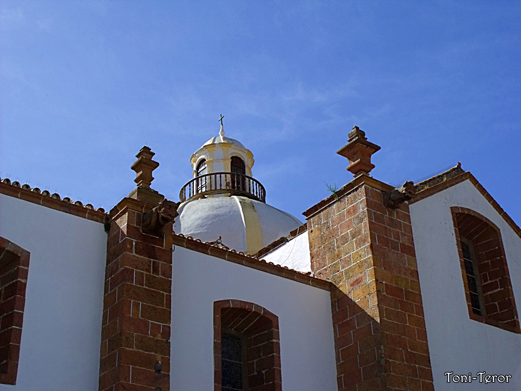 The Basílica del Pino features red volcanic stone columns and a cream‑domed bell tower.