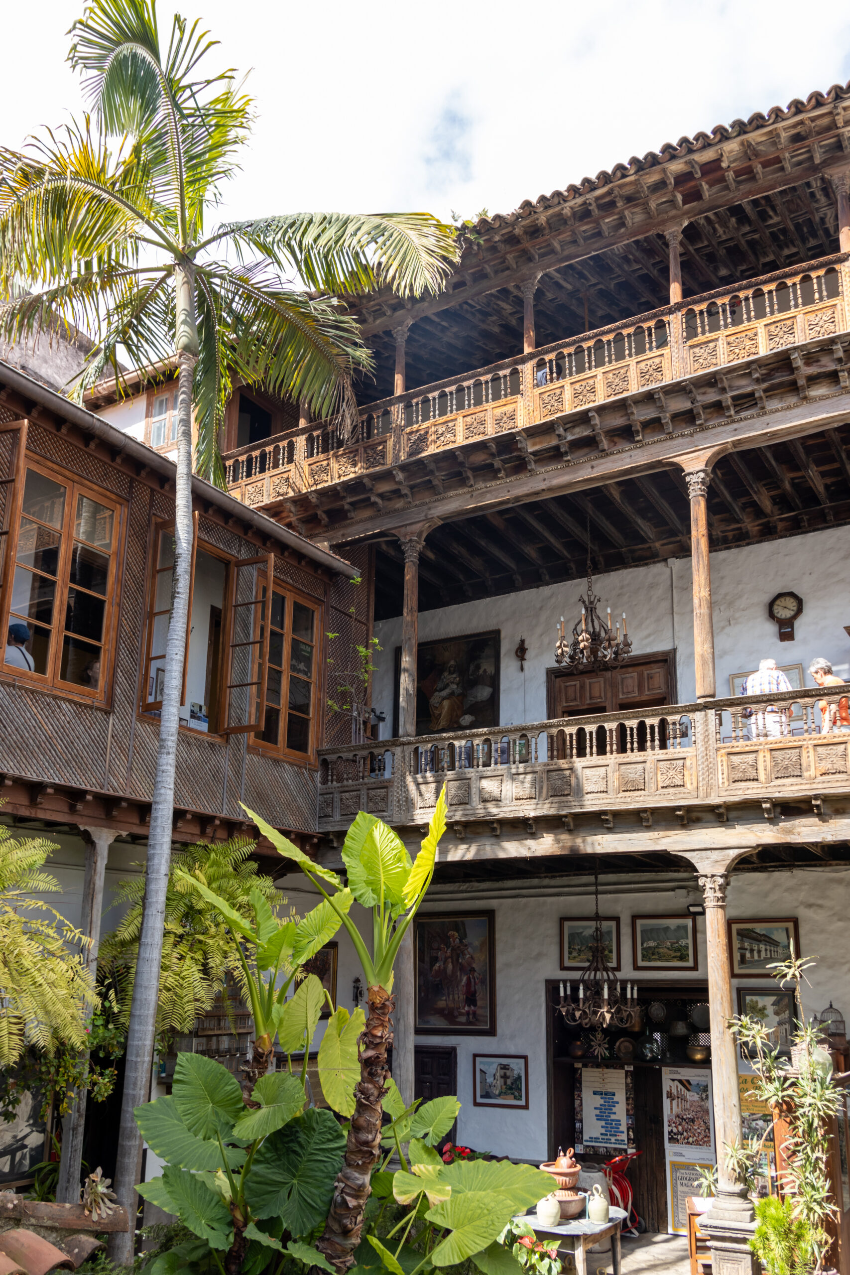 Wooden carved balconies on whitewashed colonial building with palm trees in courtyard