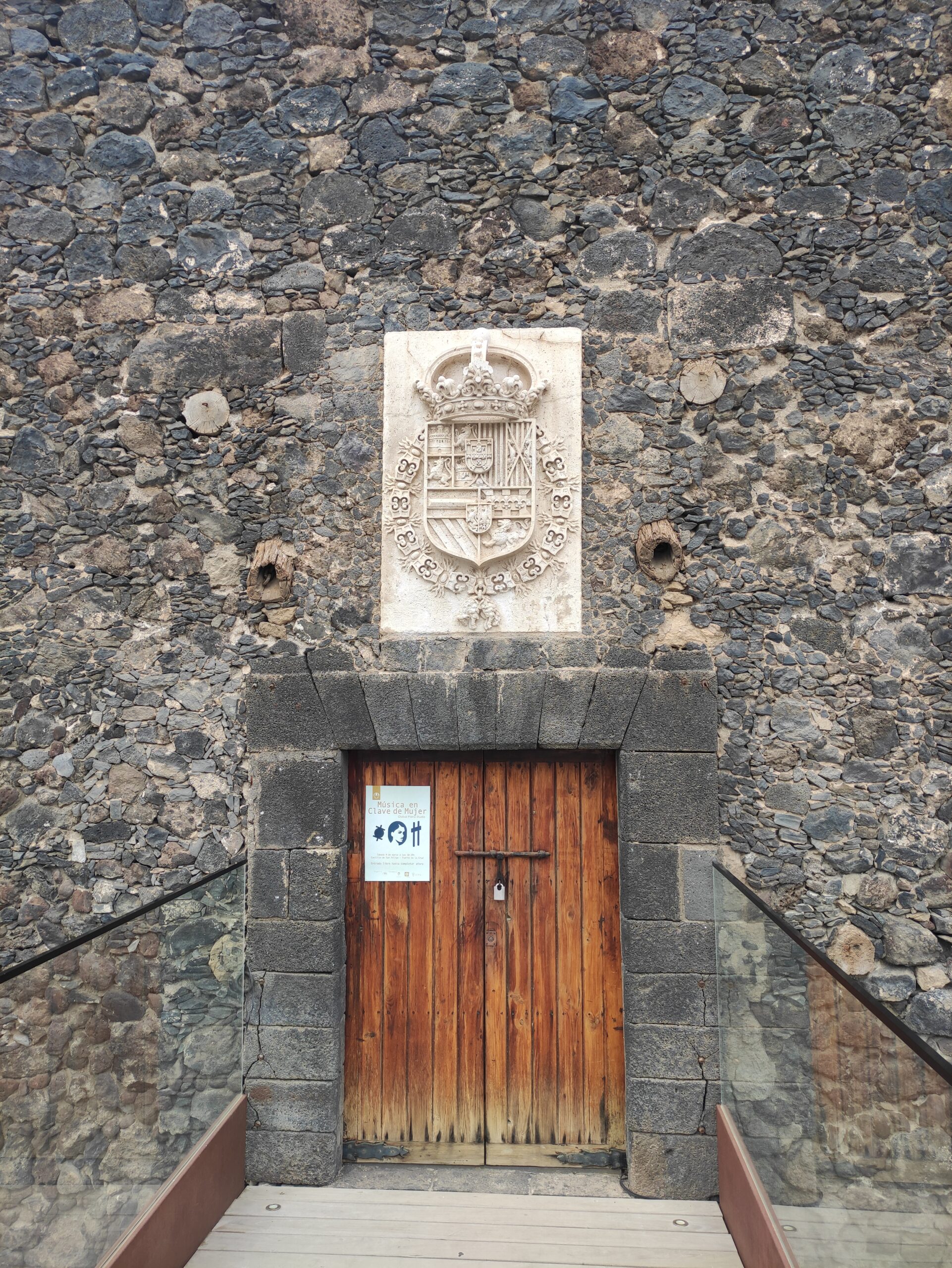 The entrance to Castillo San Felipe features a restored wooden door beneath a carved stone heraldic plaque bearing the Spanish crown.