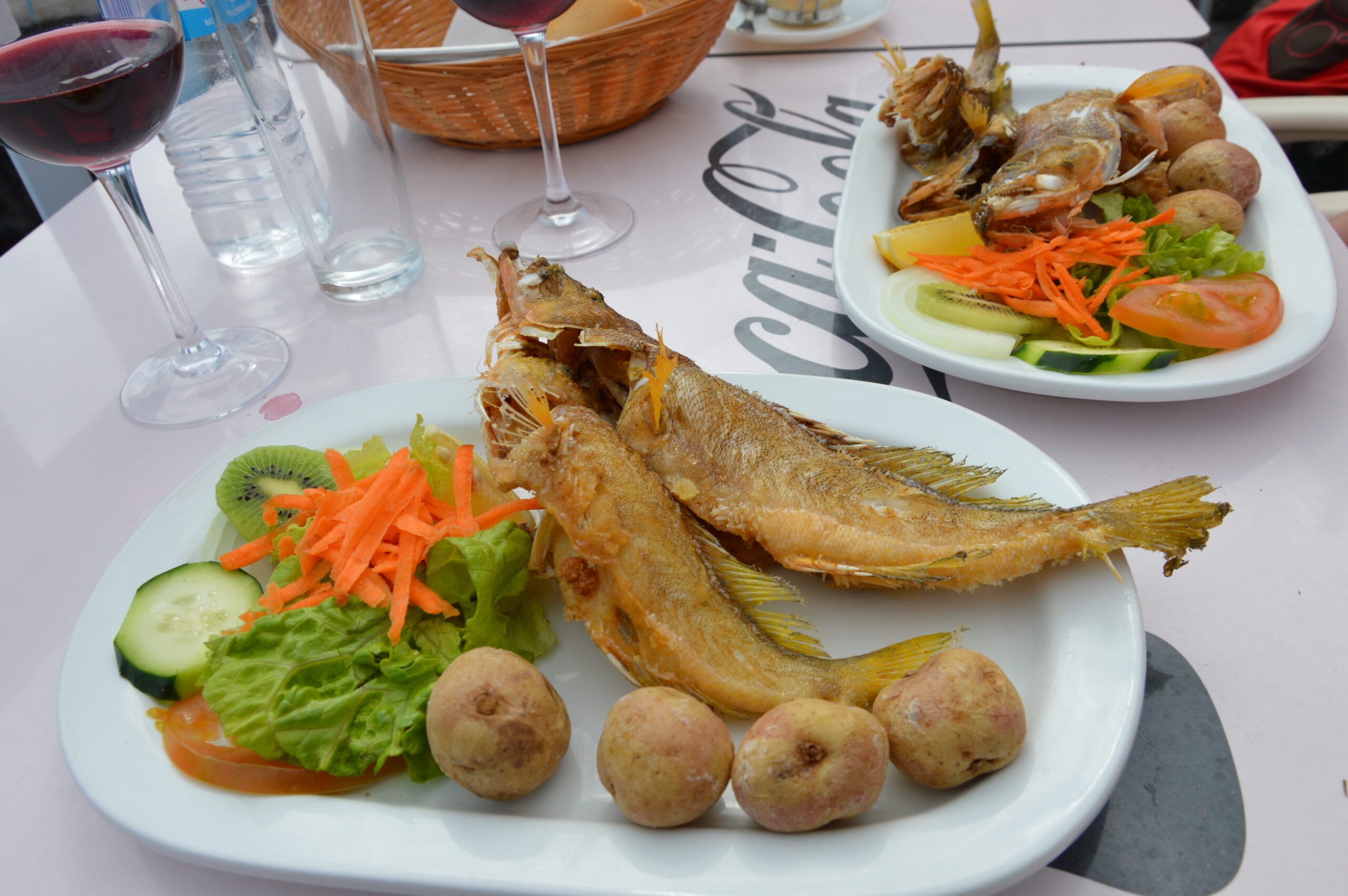 A traditional seafood meal featuring freshly fried whole fish with local potatoes and fresh vegetables, typical of Canarian dining.