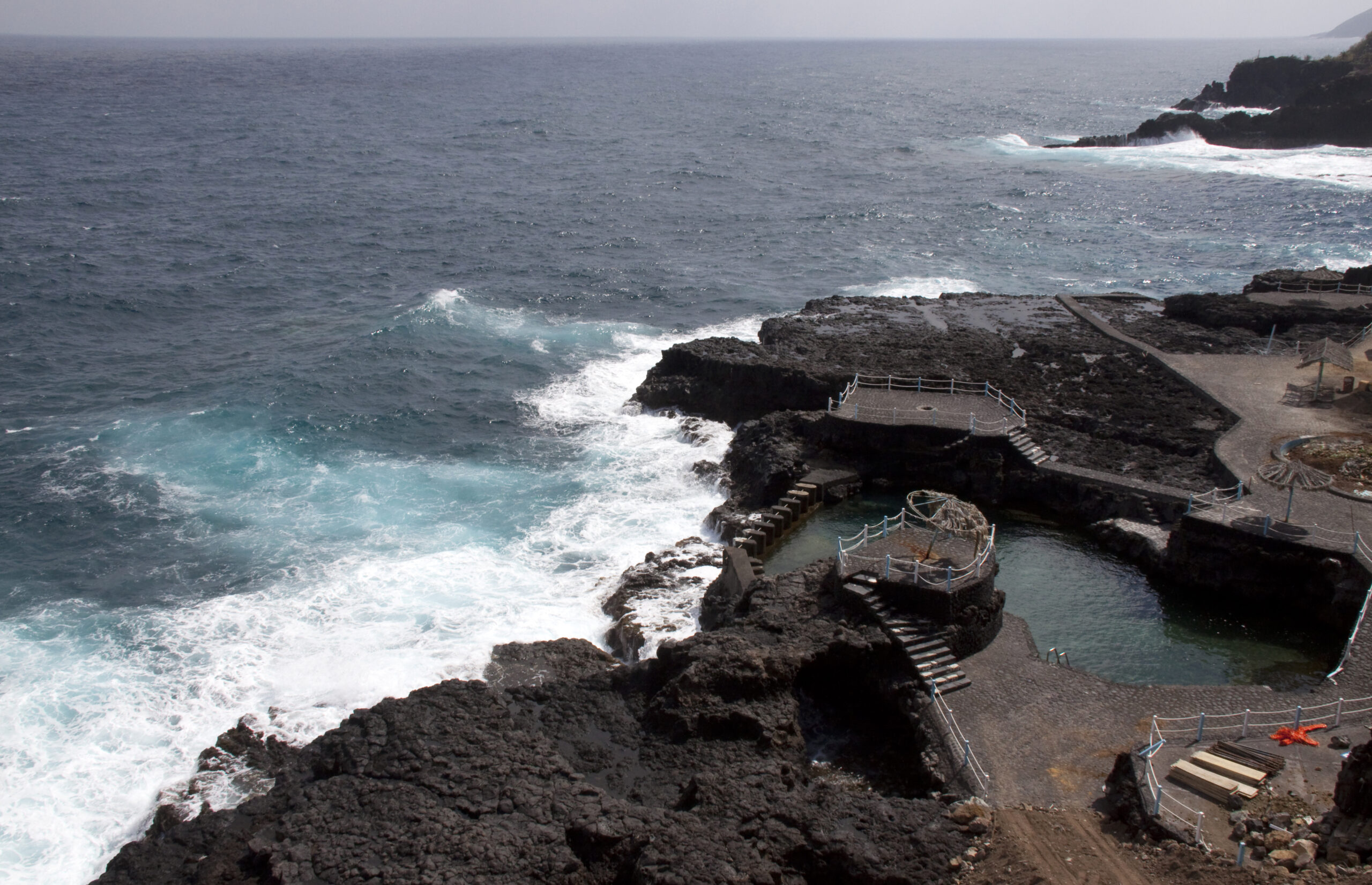 Charco Azul's natural pools carved into volcanic rock provide a sheltered swimming spot where Atlantic waves break against the rugged shoreline.