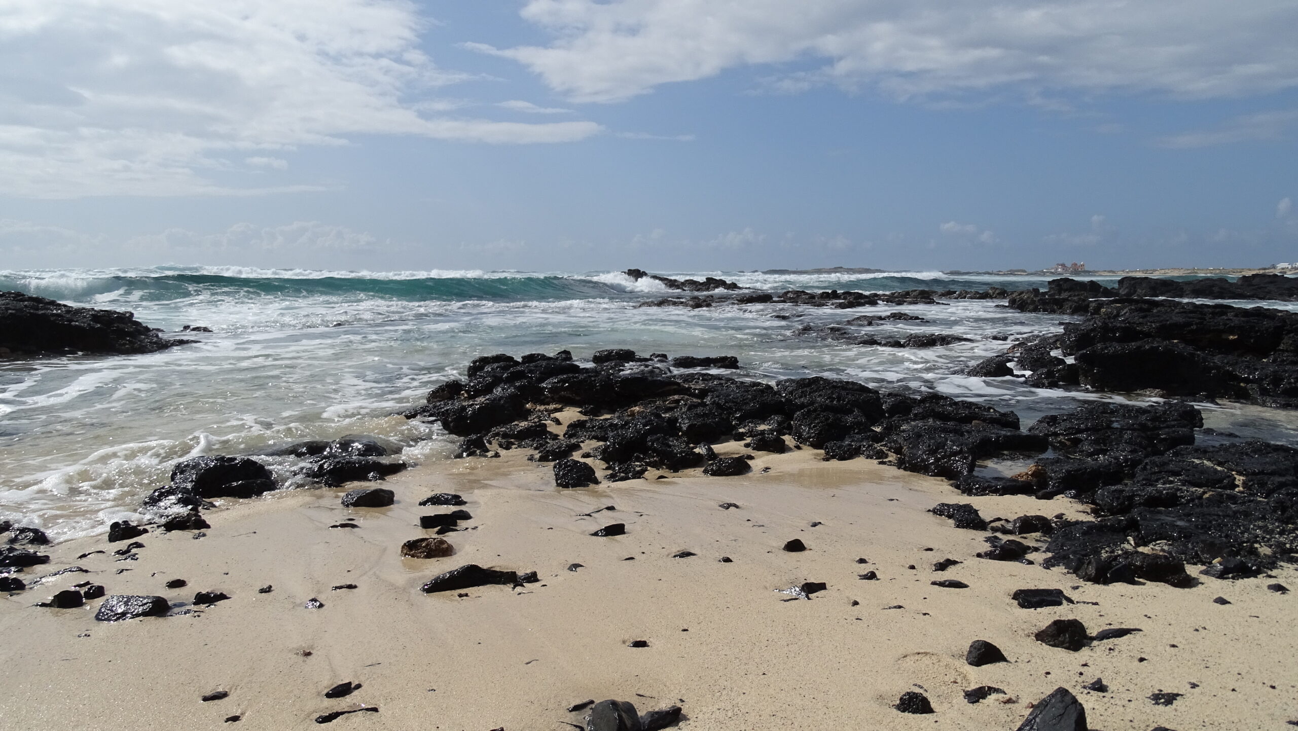 El Cotillo Beach's distinctive rocky cove features golden sand interspersed with volcanic boulders and clear turquoise waters ideal for swimming.