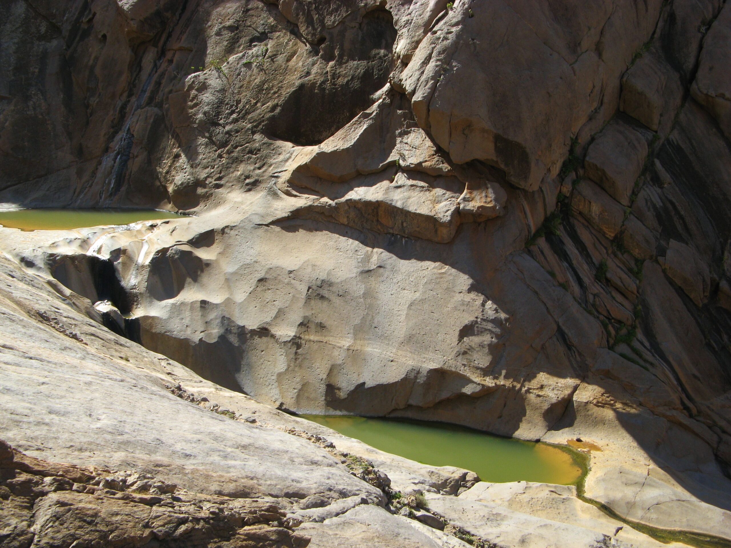 The dramatic rocky gorge of Embalse de las Peñitas reveals its striking green waters nestled beneath towering stone formations.