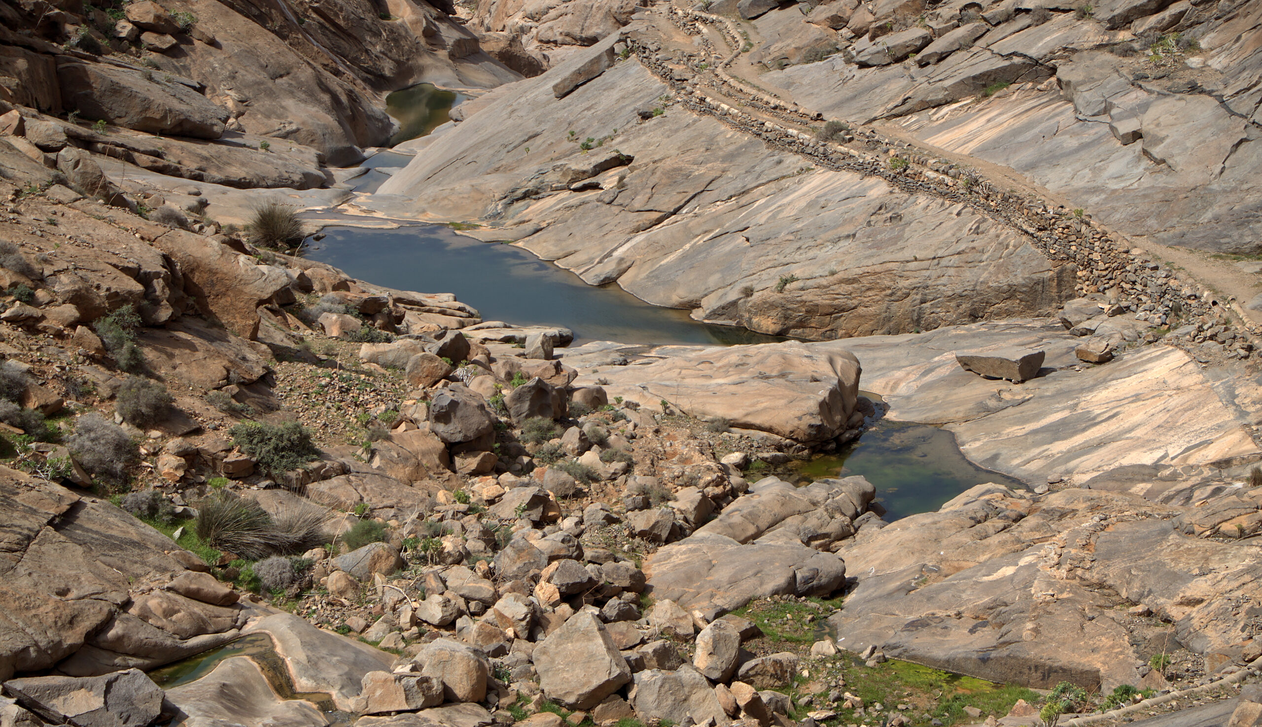 Natural rock pools and layered stone formations at Embalse de las Peñitas, a scenic water feature in the Betancuria region.
