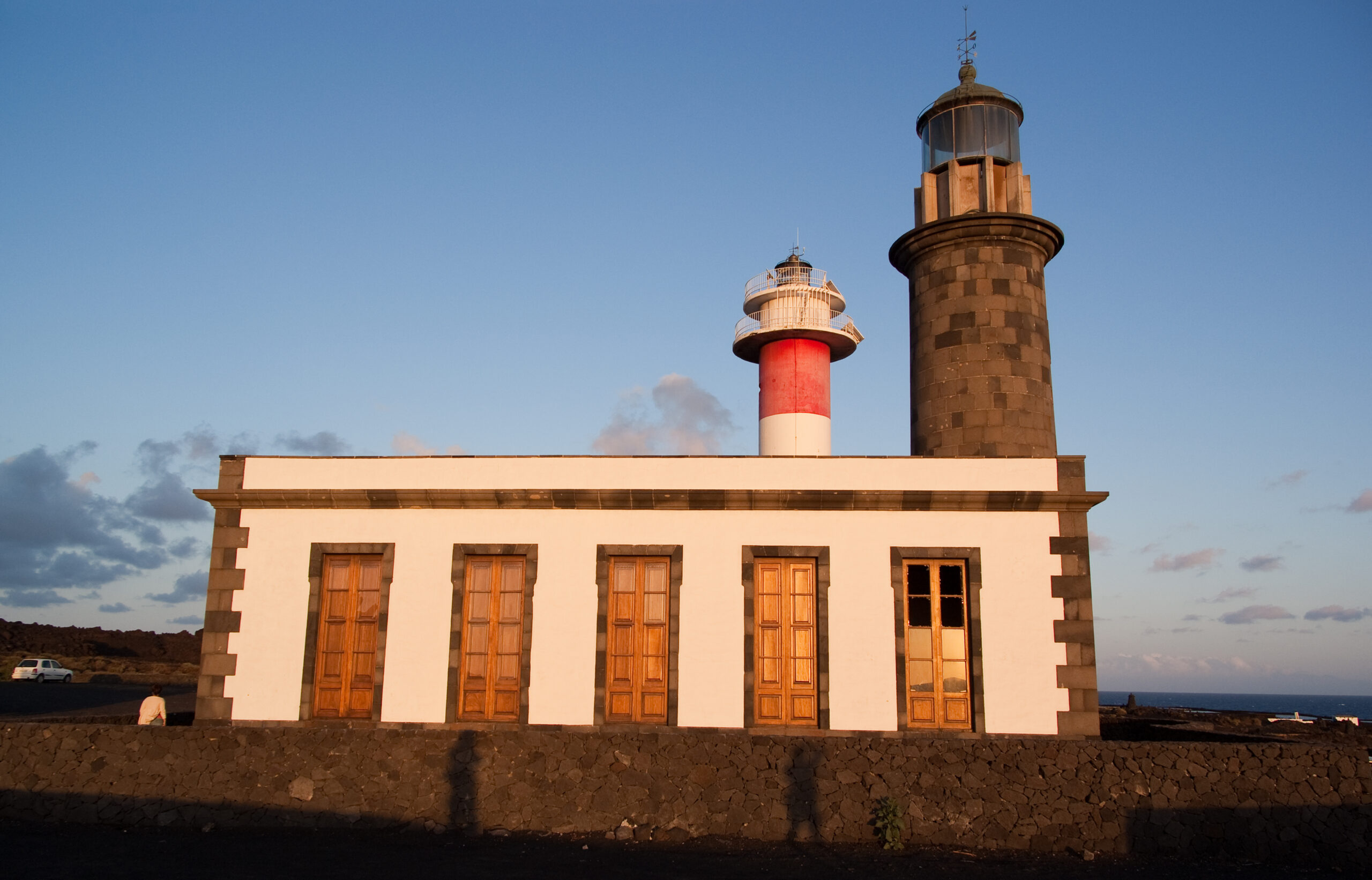 The distinctive lighthouse complex at Faro de Fuencaliente features a white keeper's residence with twin lighthouse towers overlooking the volcanic coast of La Palma.