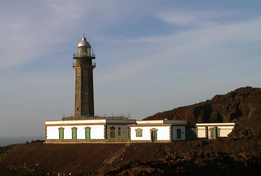 Faro de Orchilla, a historic lighthouse on El Hierro's westernmost point, stands sentinel above its keeper's quarters on the volcanic coastline.