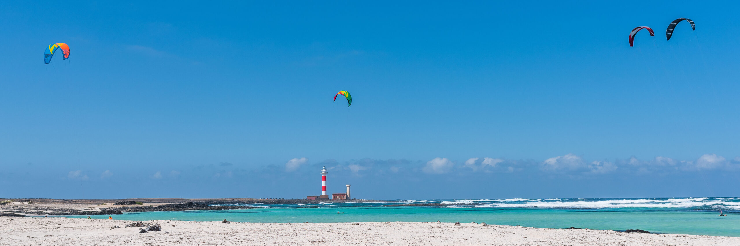 Faro del Tostón lighthouse stands sentinel over the turquoise waters of El Cotillo, a popular spot for kite surfers and beach enthusiasts.