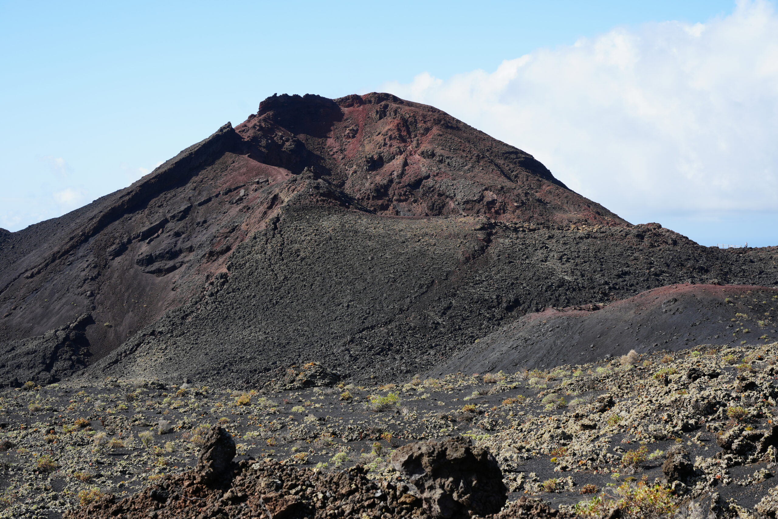 A volcanic cinder cone at Fuencaliente displays the stark geology of La Palma's volcanic landscape, with dark lava rock and distinctive crater formation.