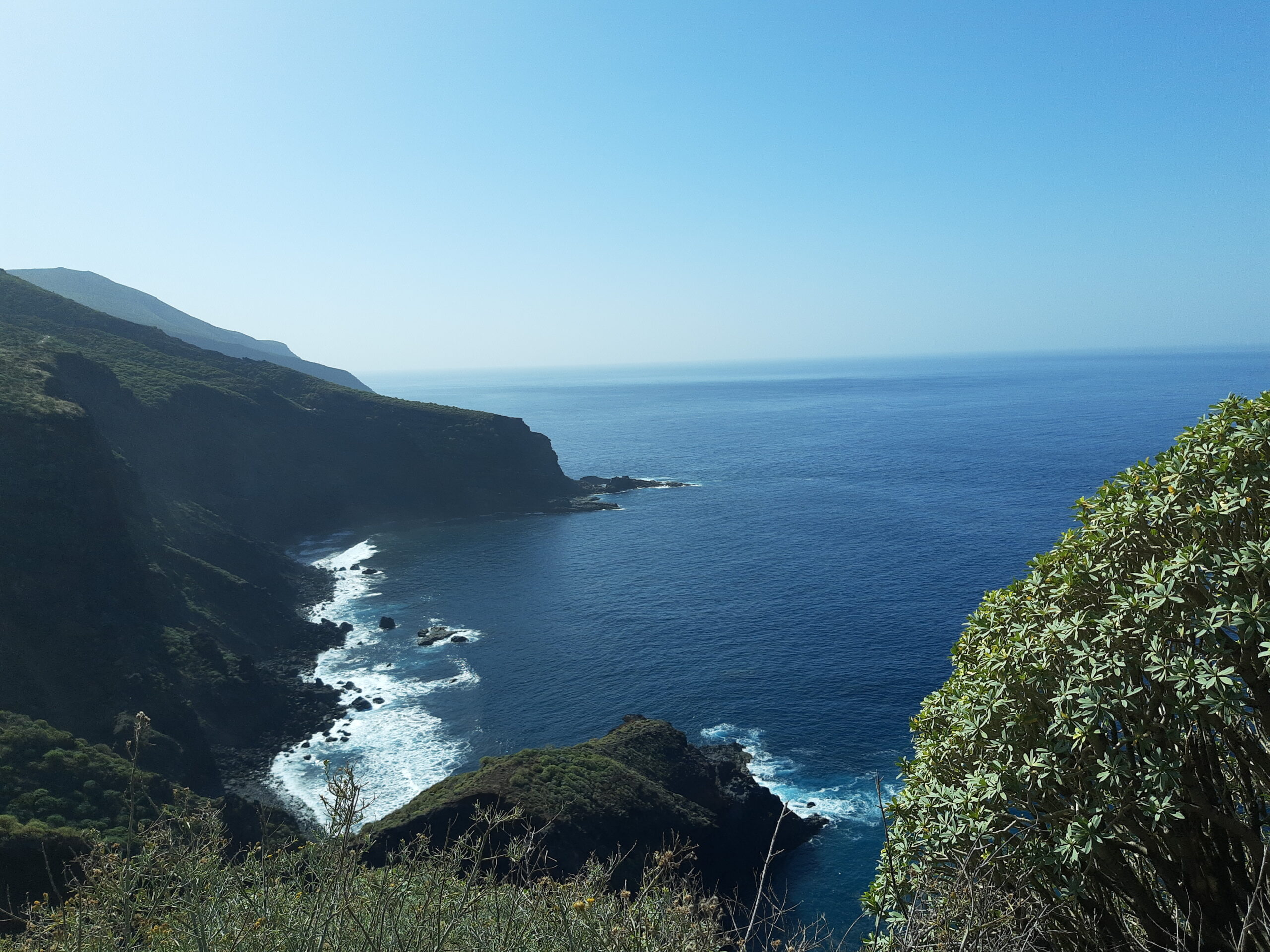 The dramatic Garafía Coast features rugged volcanic cliffs plunging into the Atlantic, with waves breaking against dark rock formations.