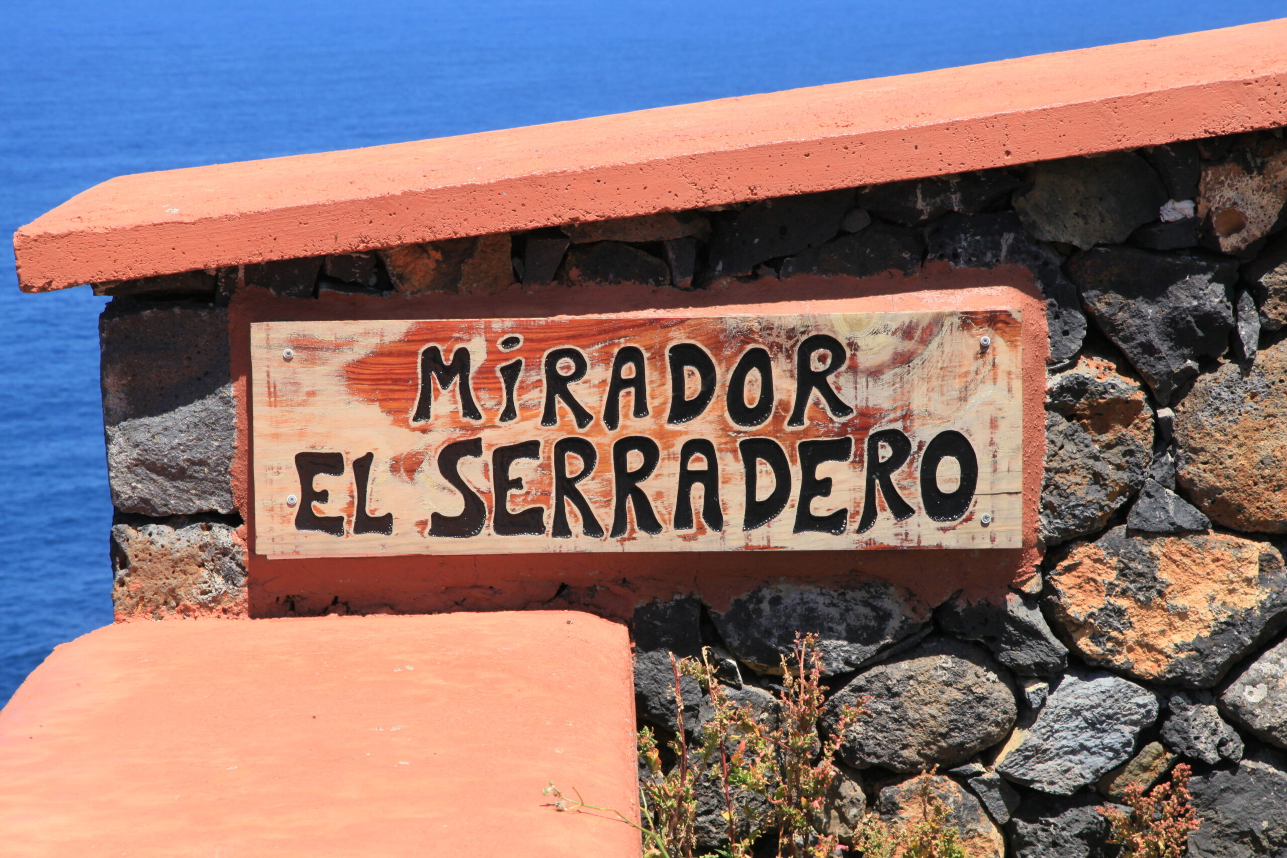 A rustic sign marks Mirador El Serradero, a viewpoint on La Palma's Garafía coast overlooking the Atlantic.