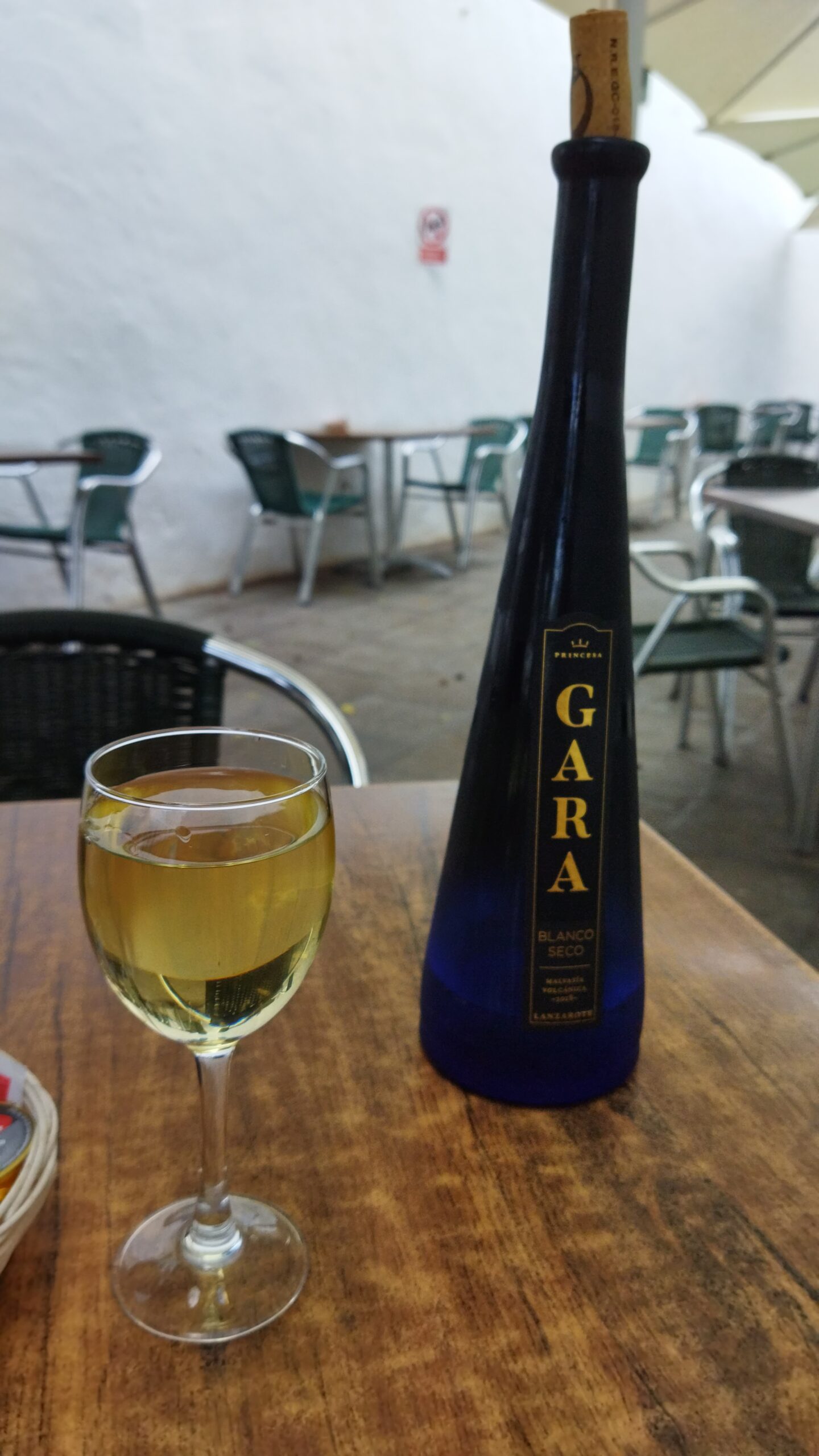 A glass of local white wine served at a terrace in Haría, paired with a bottle of Gara wine.