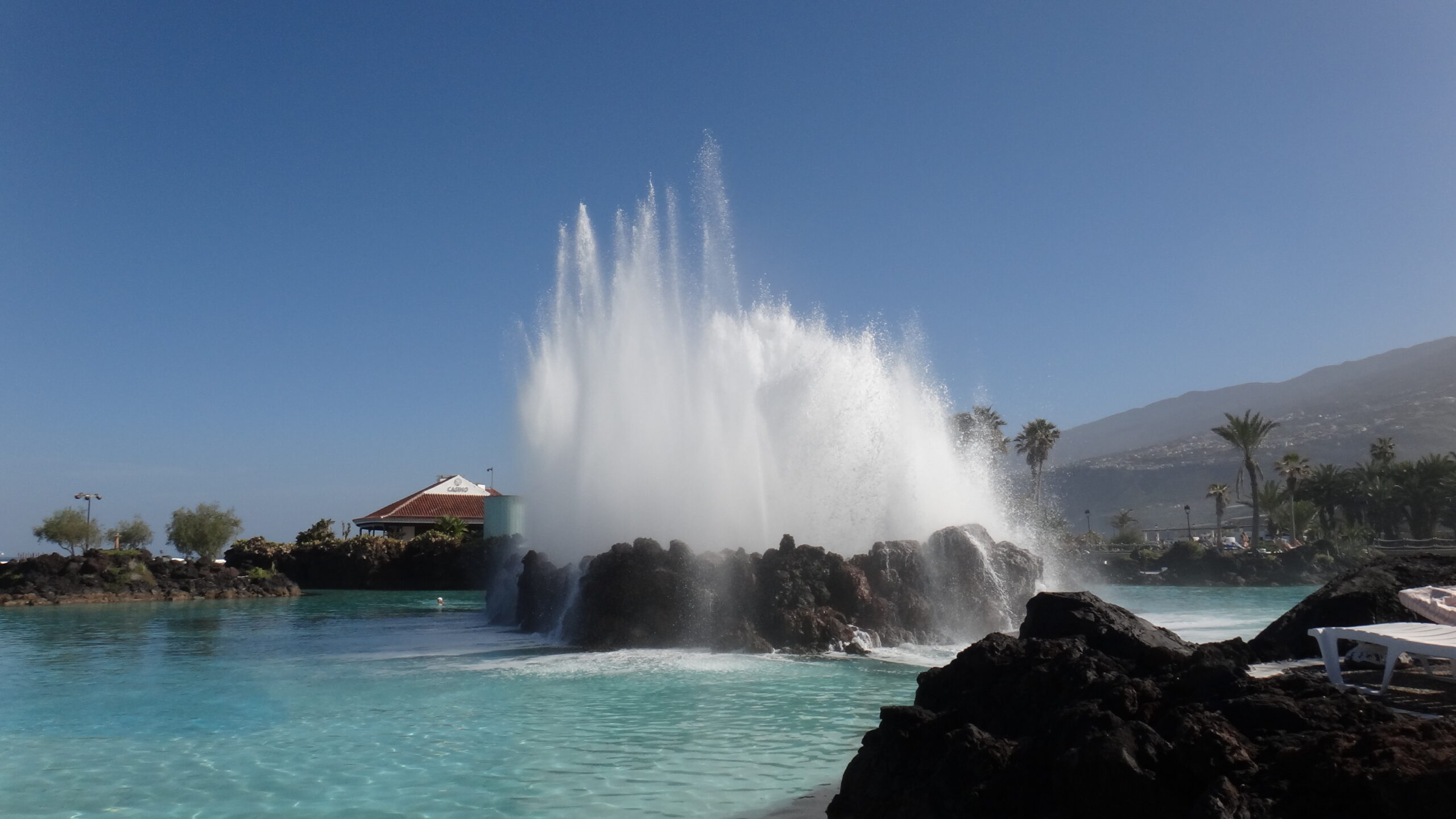Powerful Atlantic waves crash against the rocky coastline at Lago Martiánez, creating spectacular spray in the crystalline turquoise waters.