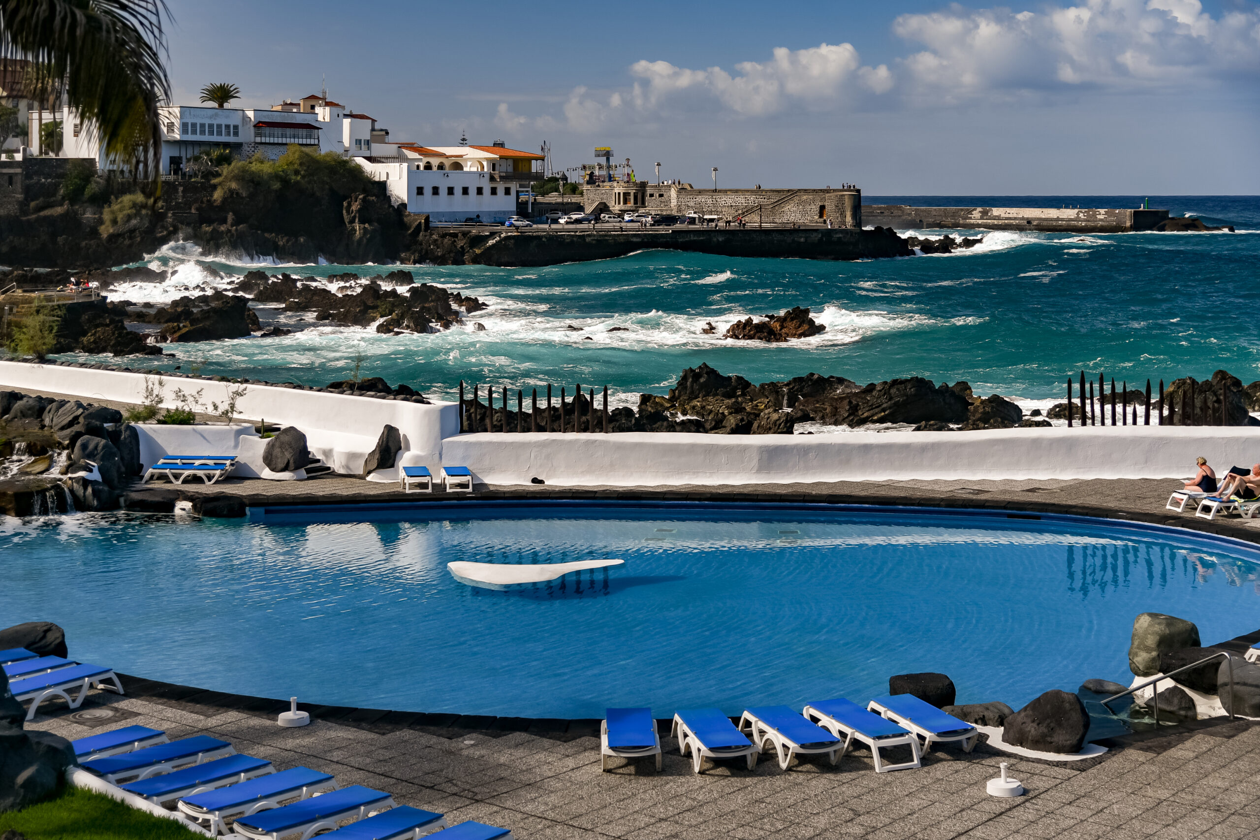 Lago Martiánez's iconic pool offers a striking contrast between its artificial blue waters and the wild Atlantic Ocean beyond, framed by traditional Canarian architecture.