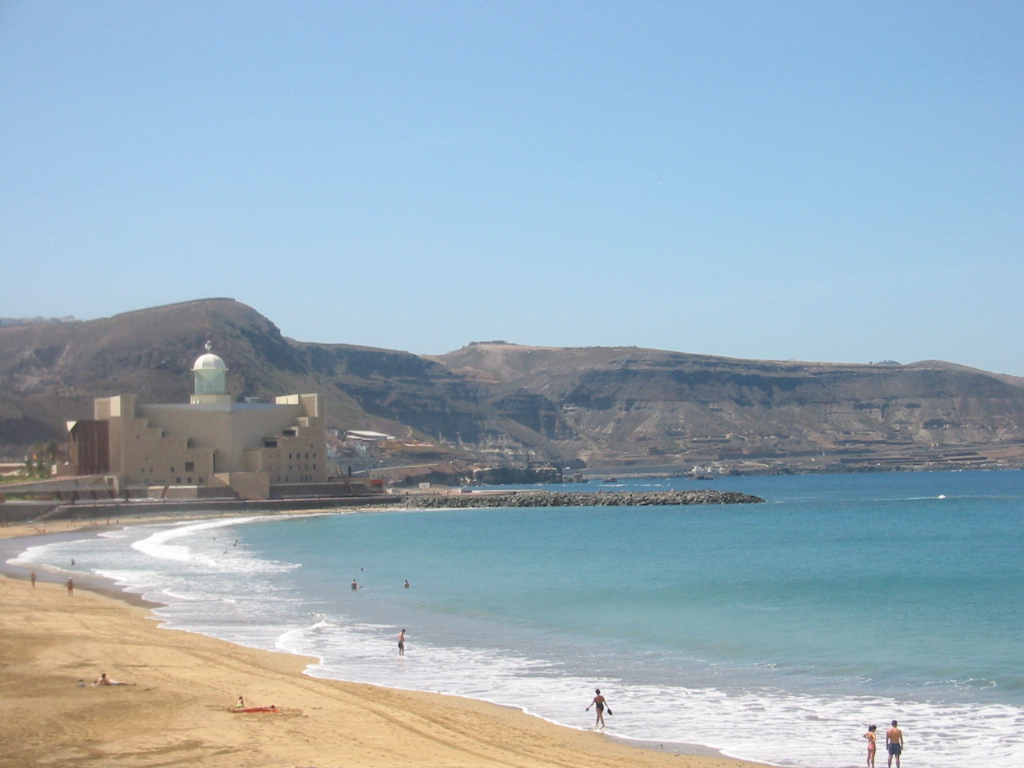 Las Canteras Beach features golden sand, clear turquoise waters, and a distinctive mosque set against dramatic volcanic hills.