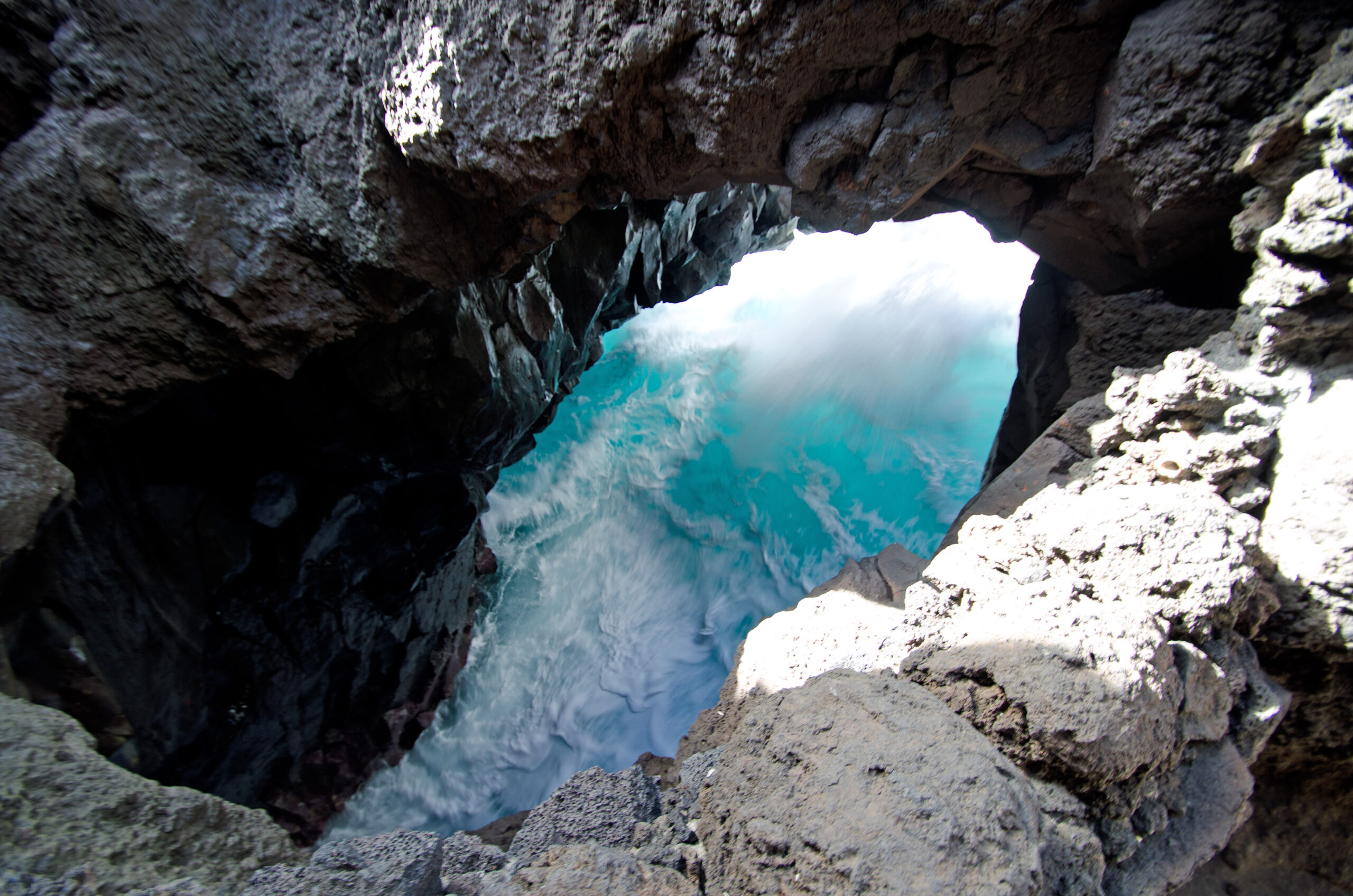 Los Hervideros features dramatic volcanic rock formations with natural arches that frame the vibrant Atlantic waters below.
