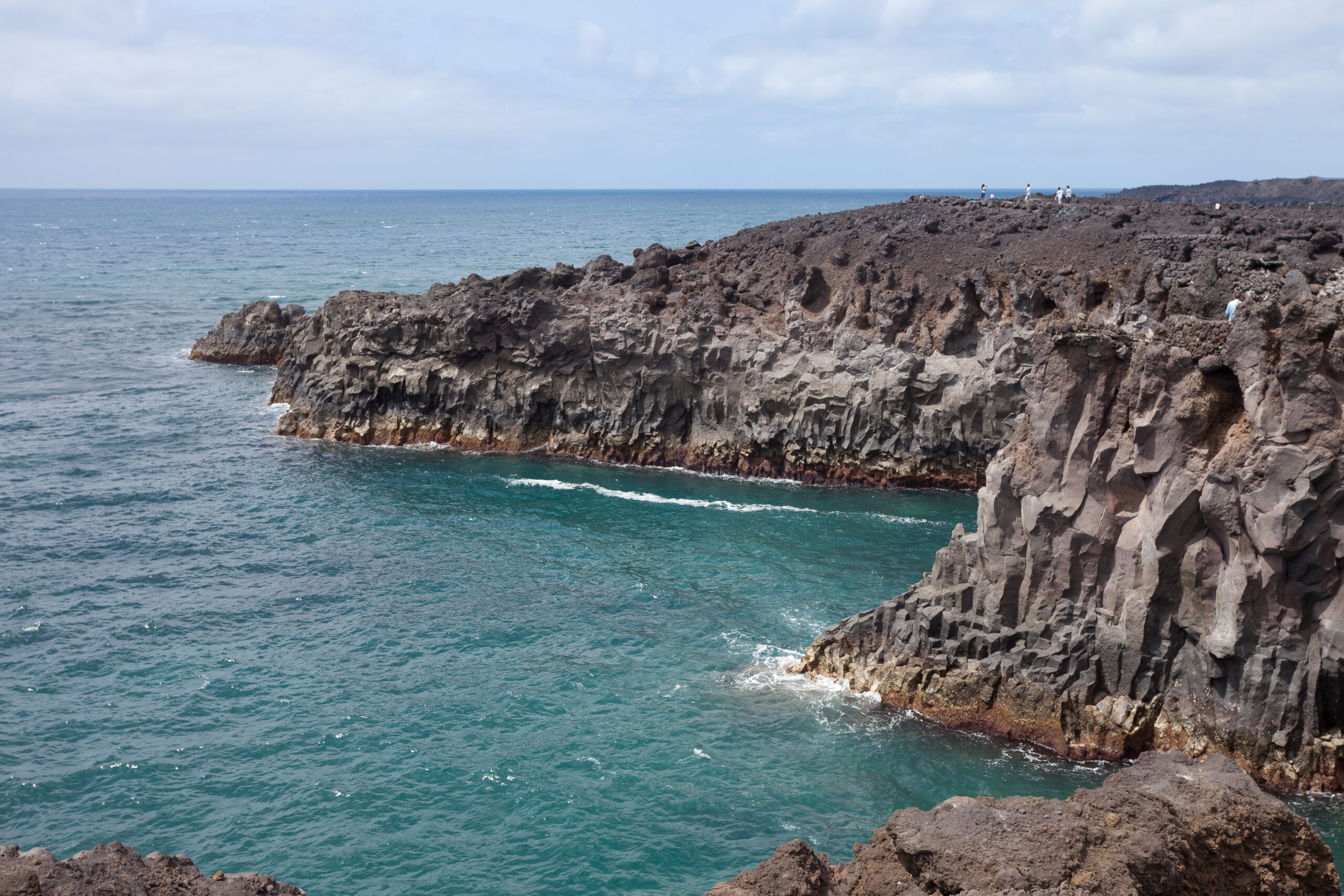 Los Hervideros features striking volcanic rock formations with geometric columnar basalt columns overlooking the Atlantic Ocean.