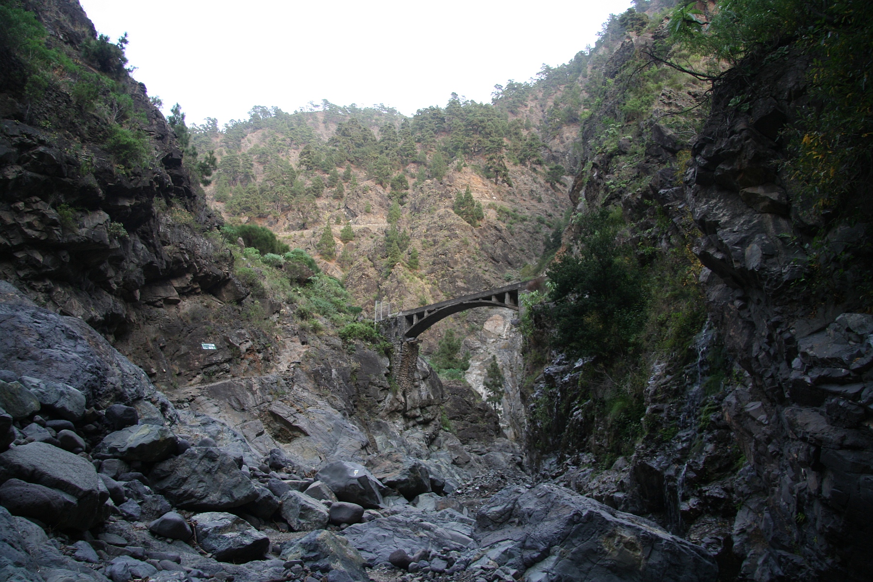 A stone bridge crosses the dramatic ravine within the volcanic landscape of Caldera de Taburiente.