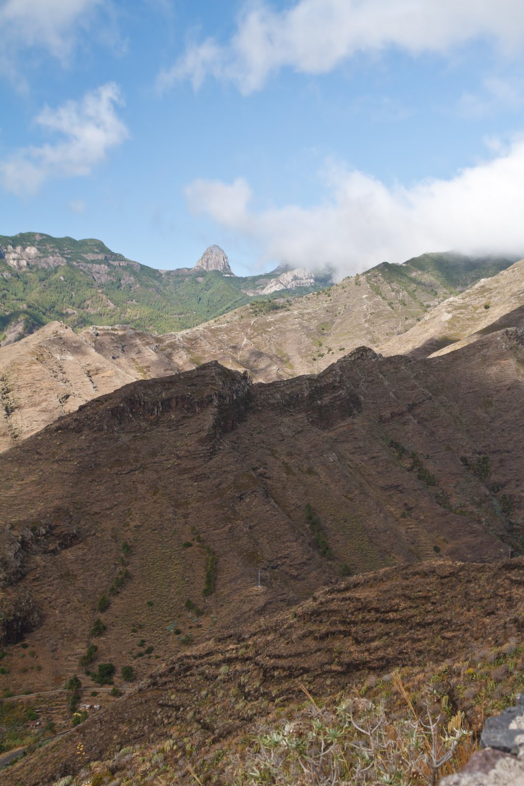 Majona Natural Park features dramatic volcanic terrain with dark lava flows and lush mountain vegetation beneath a distinctive rocky peak.