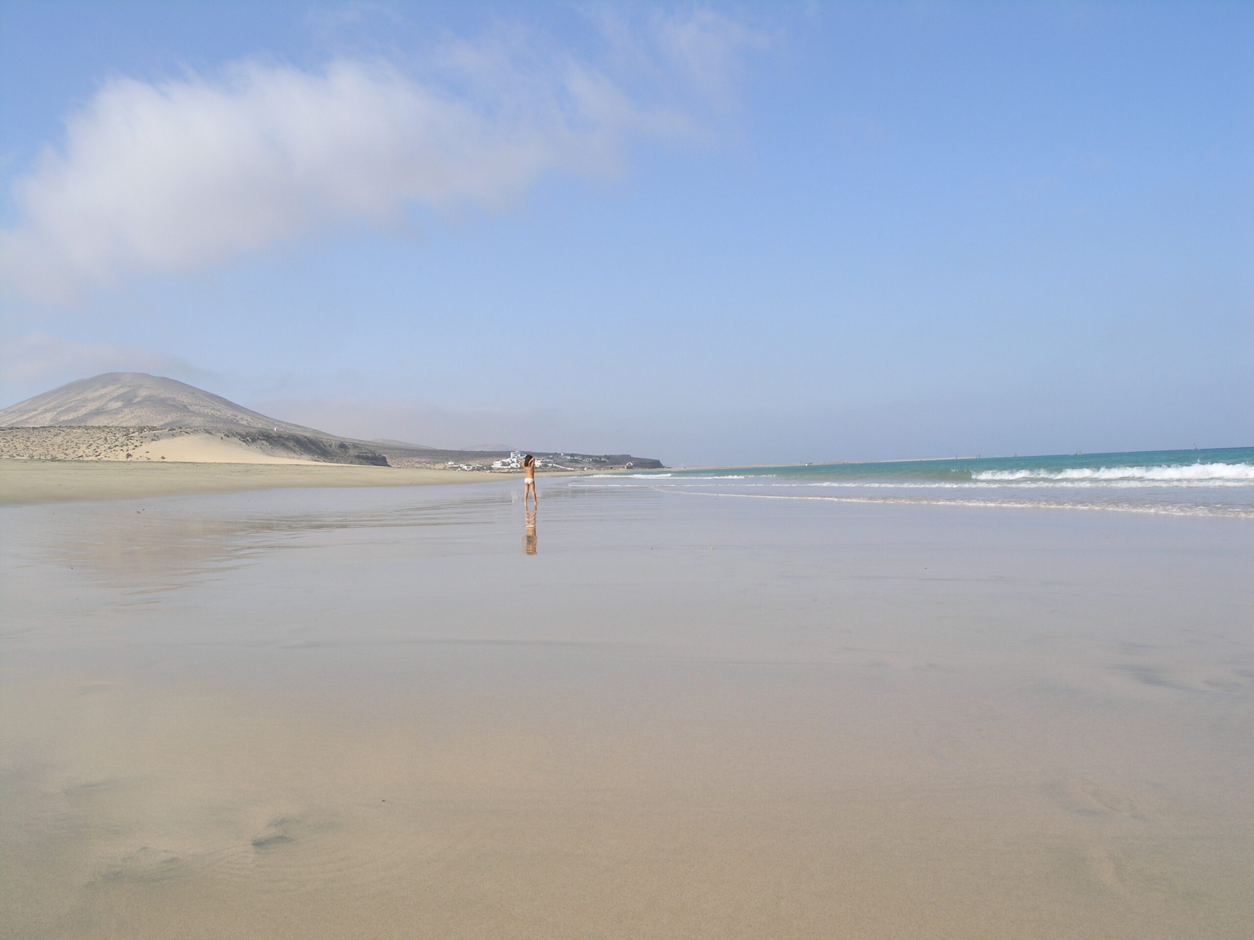 Mal Nombre Beach stretches wide and pristine, with volcanic peaks framing the sandy shoreline and Atlantic waves rolling toward the coast.
