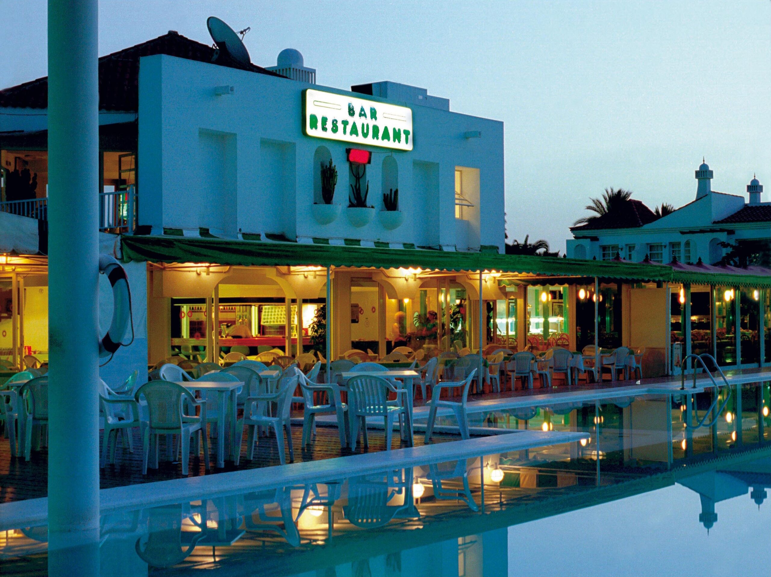 A turquoise‑painted bar‑restaurant reflects the relaxed evening atmosphere of Maspalomas.