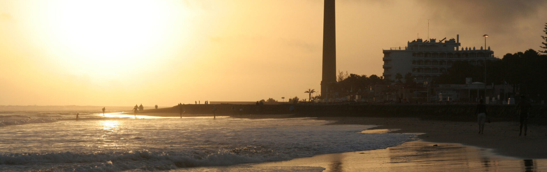 Lighthouse silhouetted against golden sunset light.