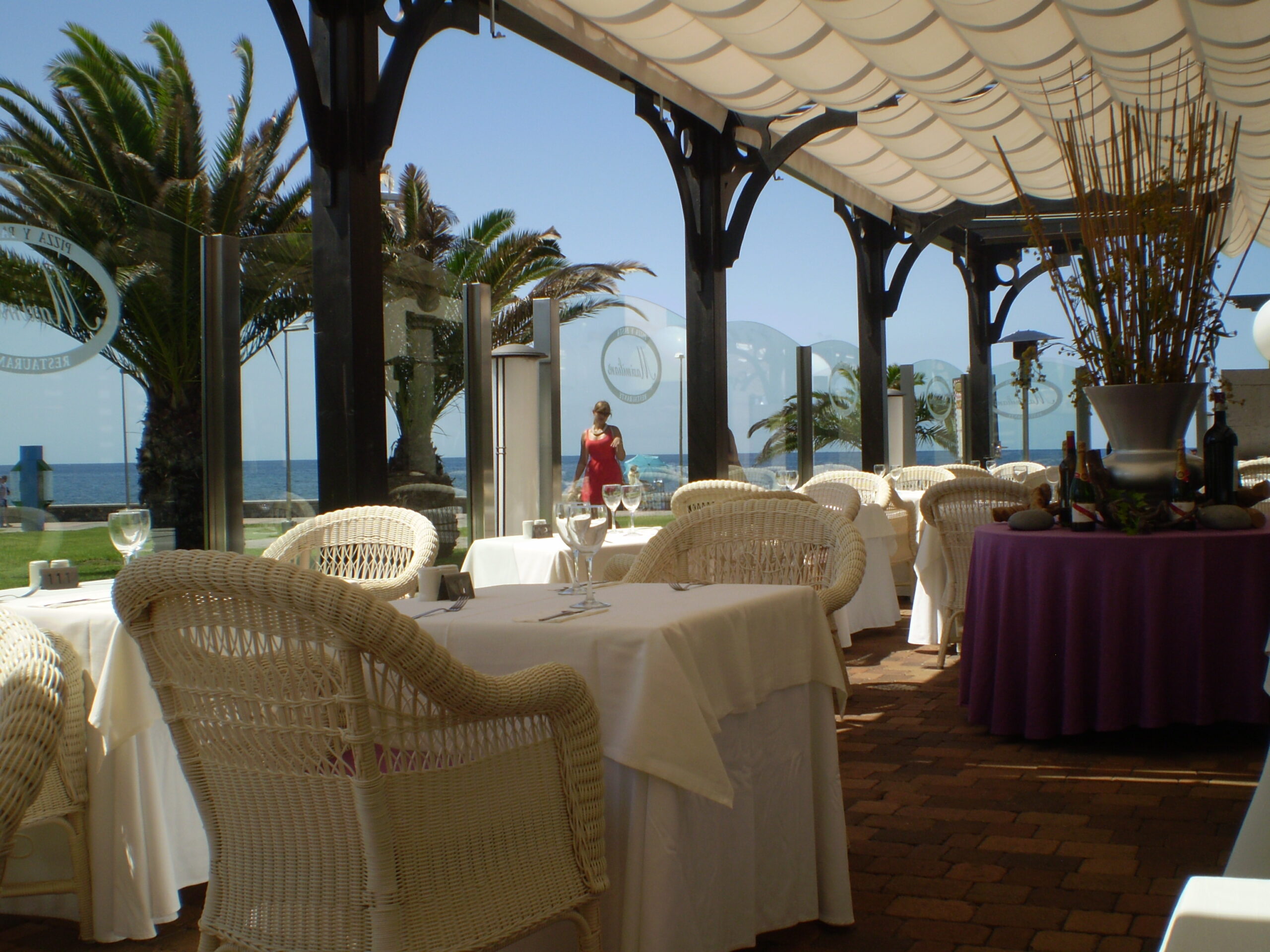 Cafés and palm‑lined terraces sit just inland from the promenade, marking the edge of the Meloneras resort front.