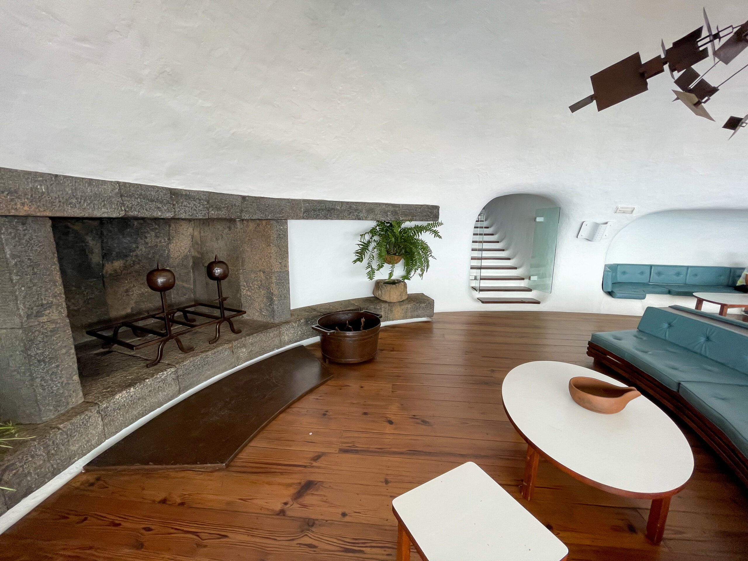 The interior of Mirador del Río features a minimalist design with natural materials, curved architectural elements, and strategic viewing windows overlooking the Canary Islands landscape.