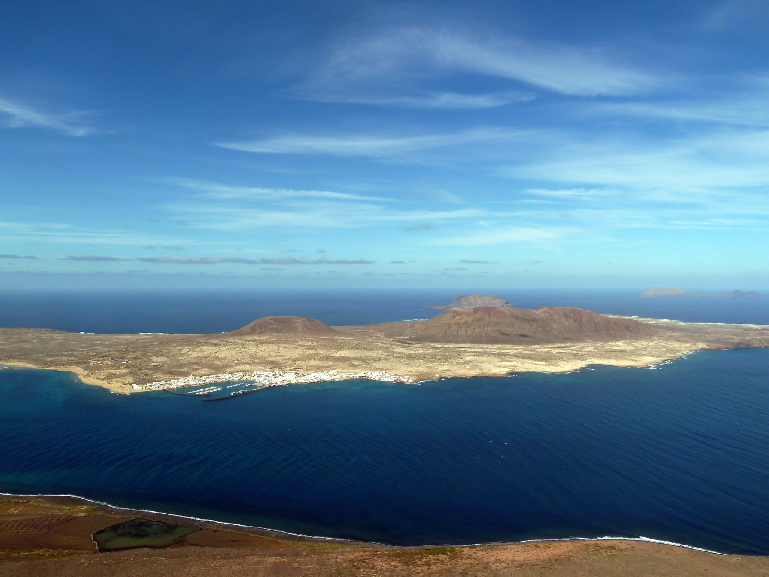 The panoramic vista from Mirador del Río reveals the neighboring island of La Graciosa with its distinctive volcanic peaks and white village nestled along the coastline.