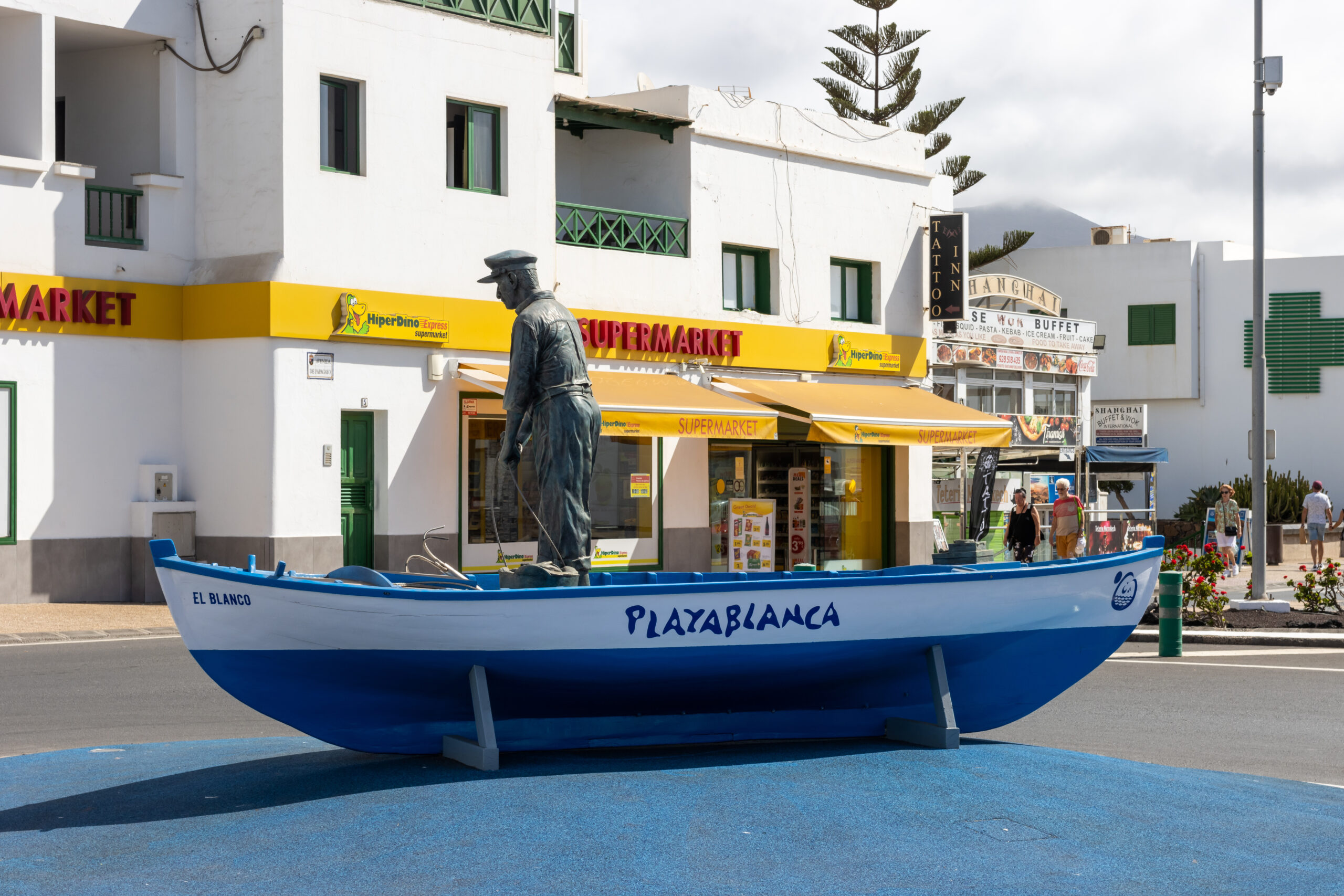 A traditional fishing boat monument in the heart of Playa Blanca village, featuring a statue commemorating the area's maritime heritage.