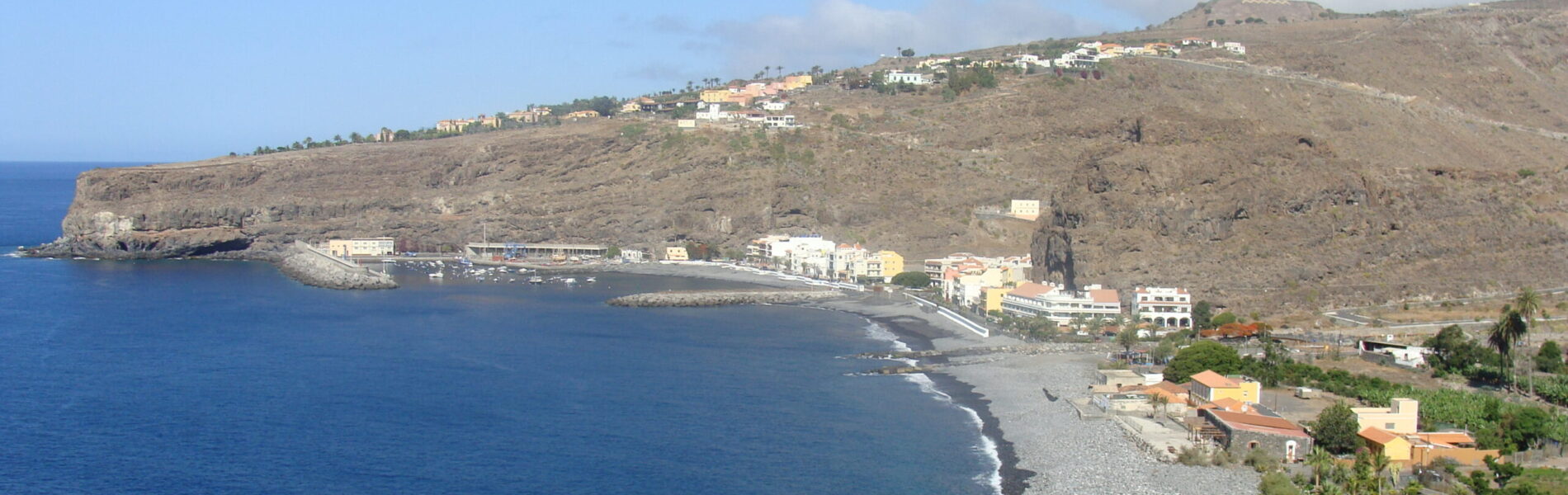 Dark sand beach with fishing boats and volcanic hills