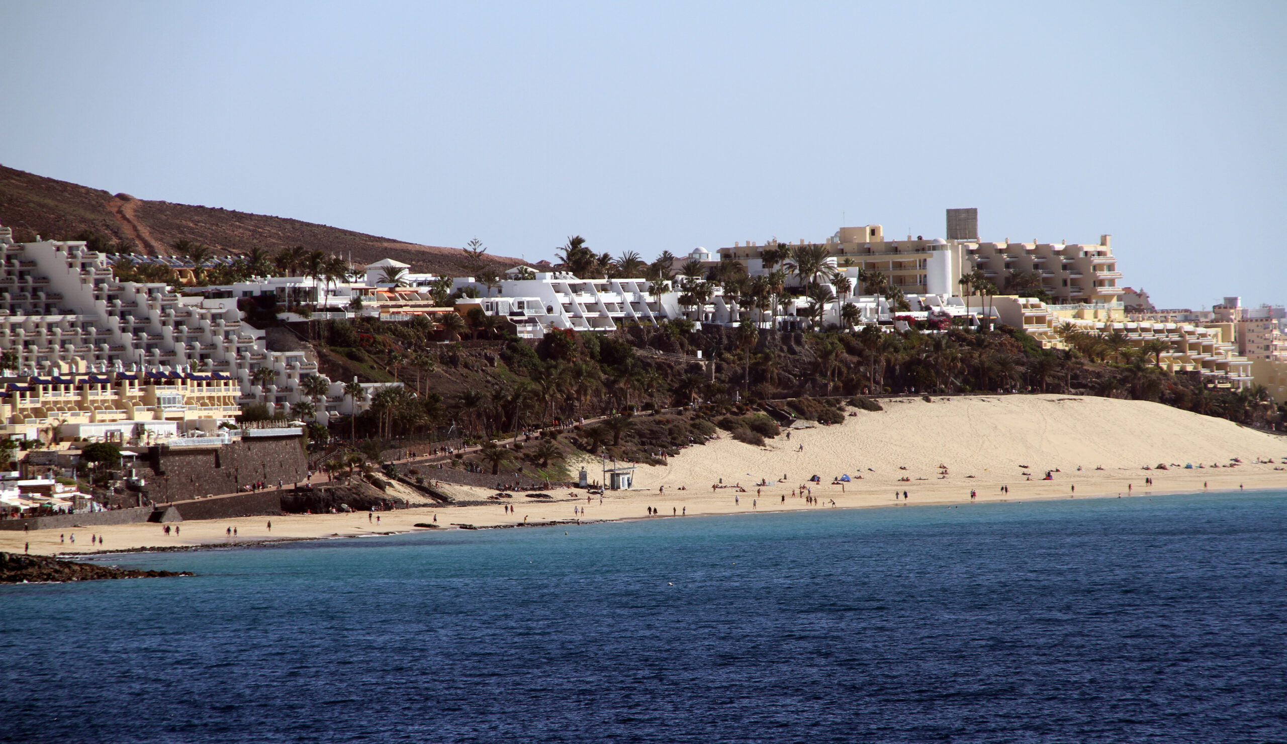 Playa del Matorral stretches along Fuerteventura's southern coast, flanked by tiered resort development and framed by turquoise Atlantic waters.