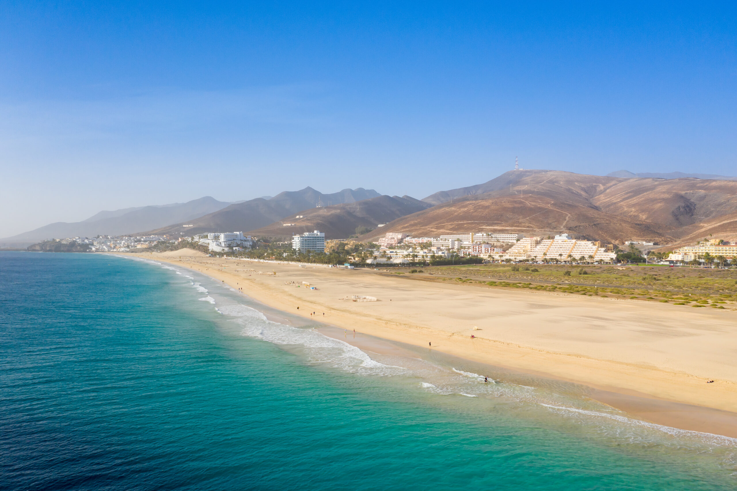 Playa del Matorral stretches along Jandía's coastline, offering golden sand and calm turquoise waters backed by volcanic hills and beachfront development.