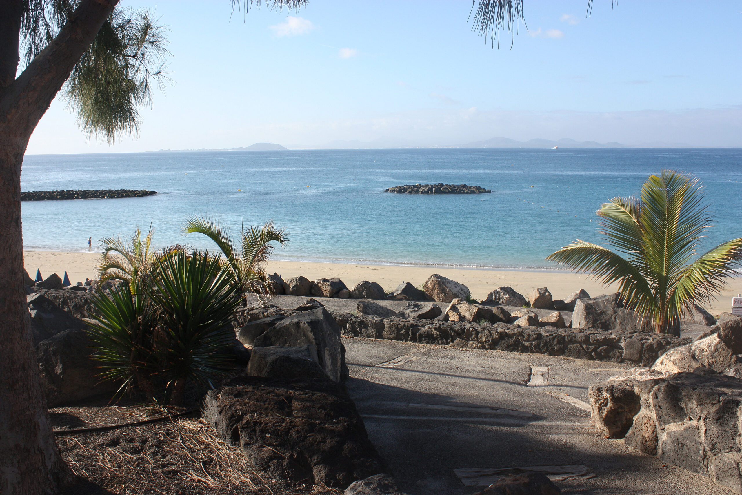 Playa Dorada's golden sand meets distinctive black volcanic rocks, with calm turquoise waters and views across to neighboring islands.