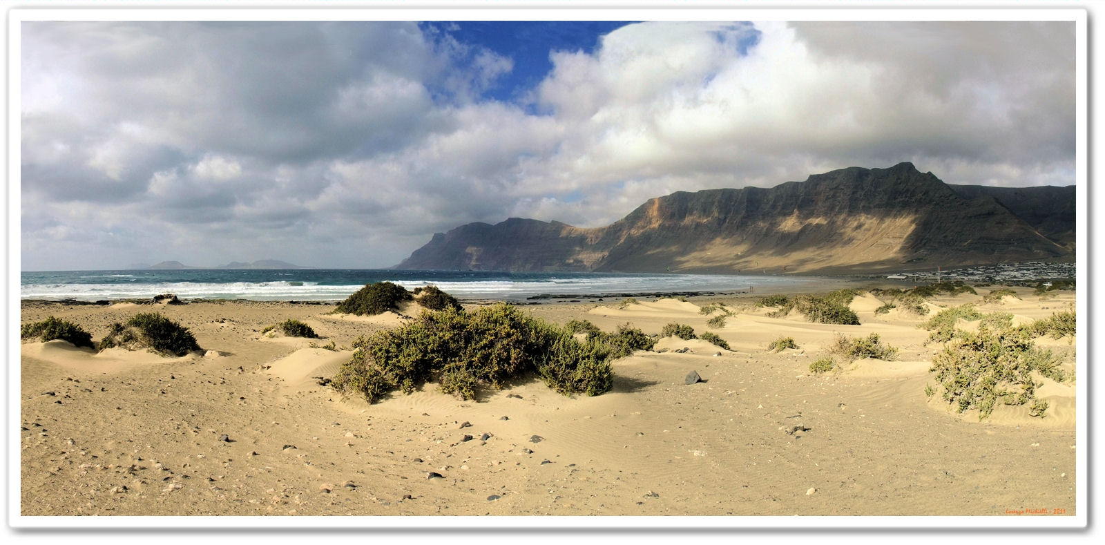 Playa Famara stretches along Lanzarote's northern coast, backed by dramatic volcanic cliffs and desert-like dunes.