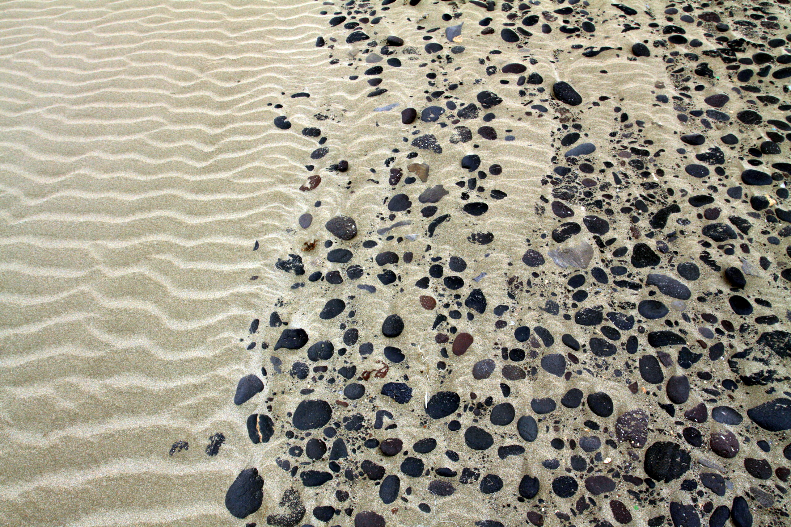 The distinctive dark volcanic pebbles mixed with golden sand are characteristic of Playa Famara's geology.