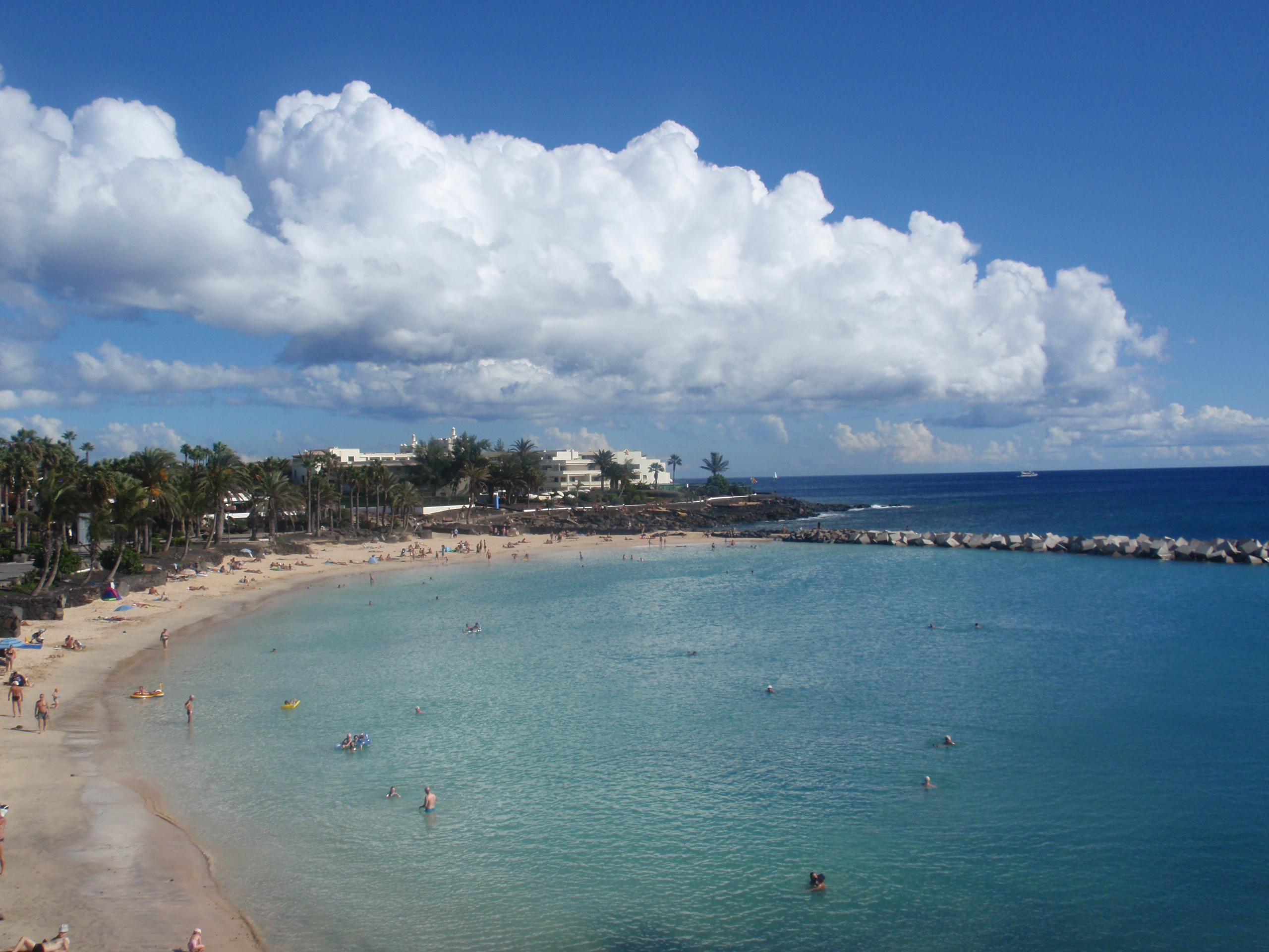 Playa Flamingo's pristine sandy beach and crystal-clear turquoise waters attract swimmers and sunbathers beneath the bright Lanzarote sun.