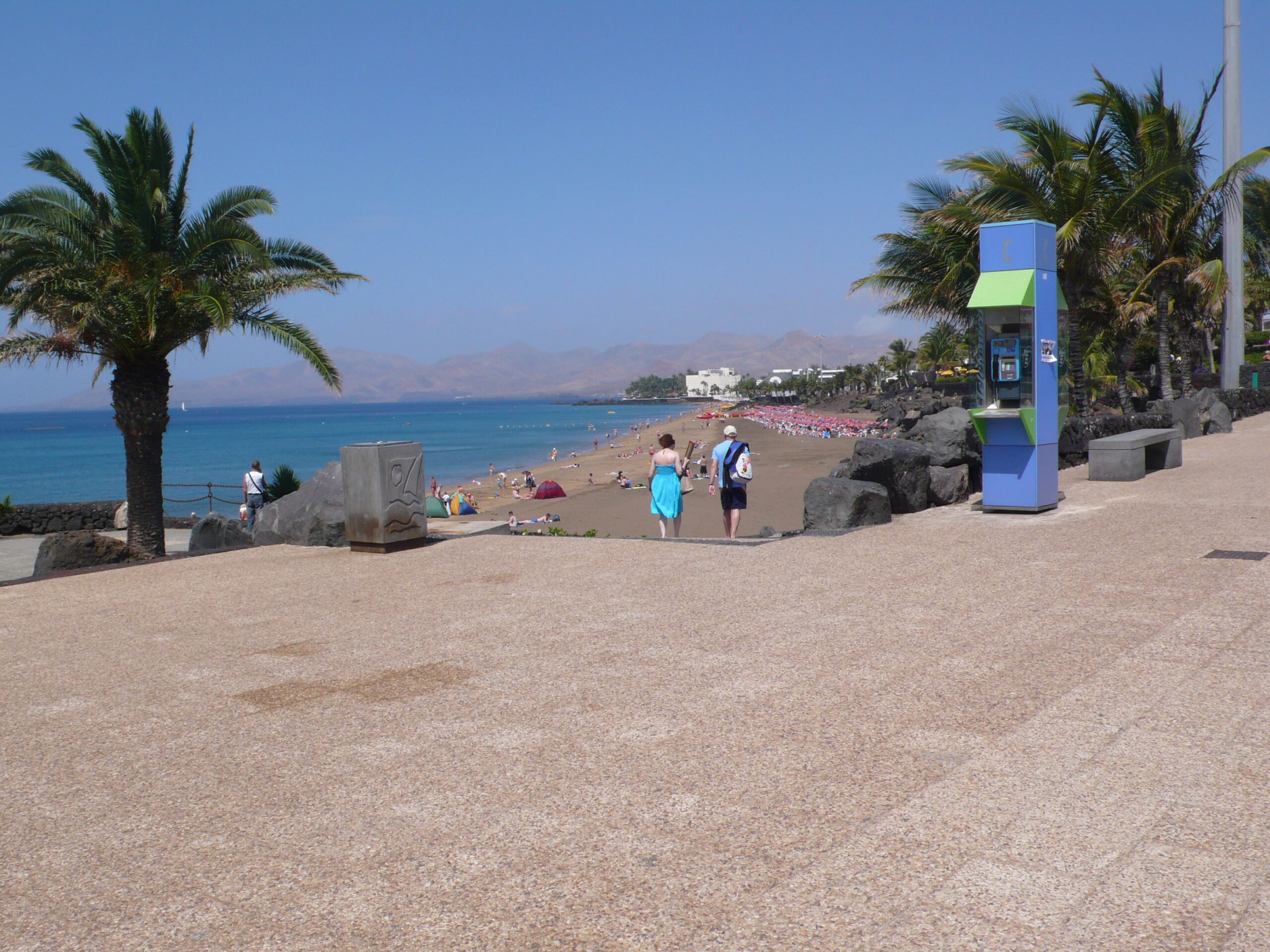 Playa Grande stretches along Puerto del Carmen's waterfront, offering golden sand, calm turquoise waters, and views of the volcanic landscape across the bay.