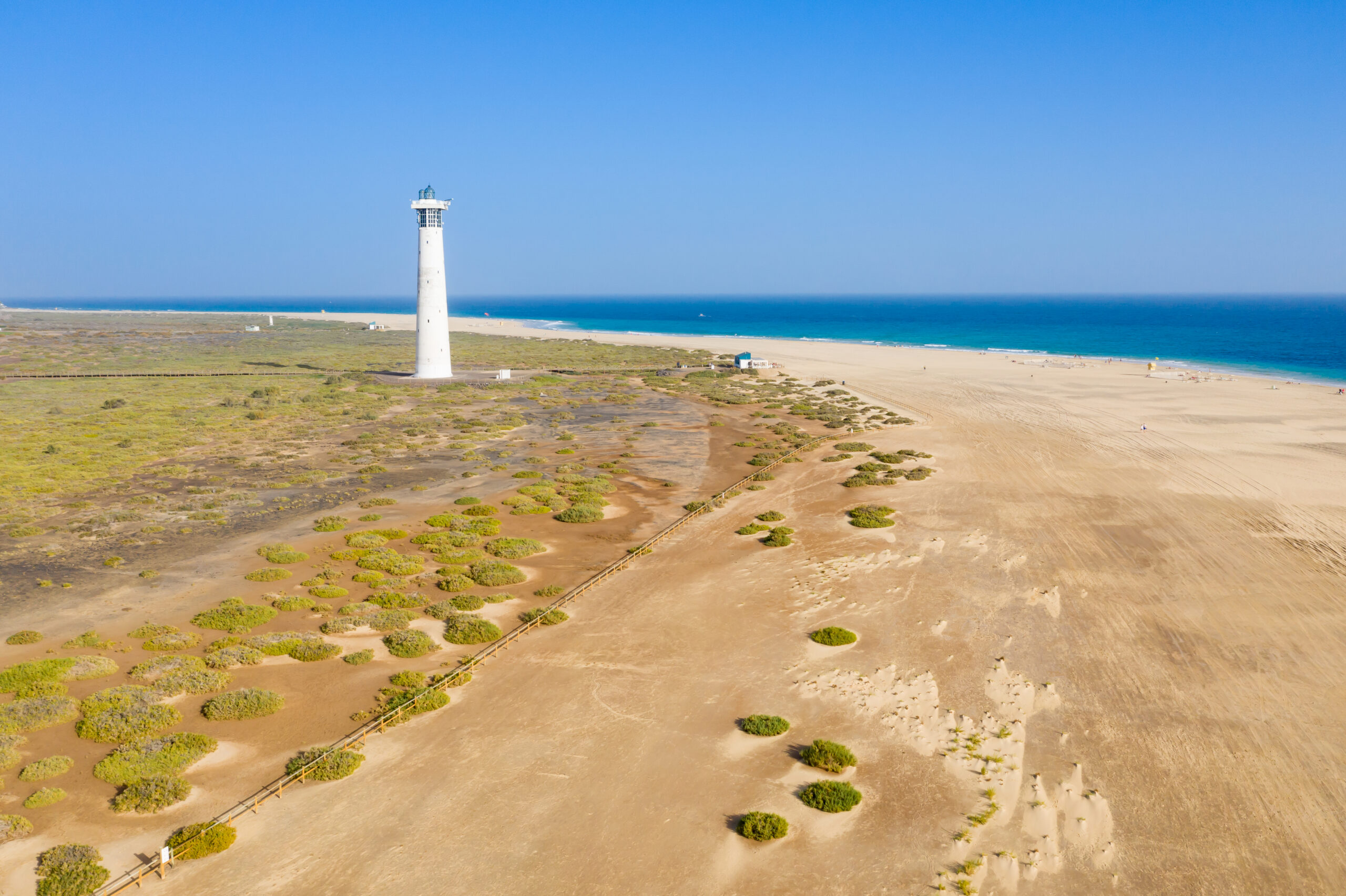 The lighthouse at Playa Morro Jable marks the southern tip of Fuerteventura, with pristine beach and open Atlantic views stretching across the peninsula.