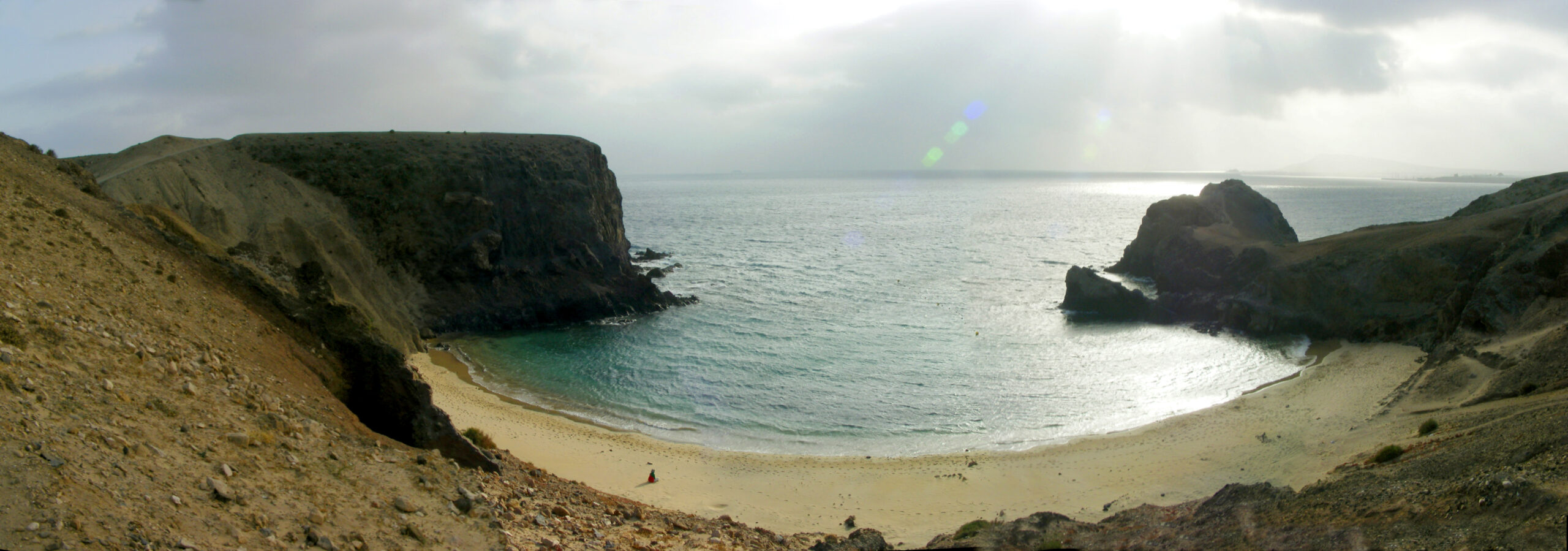 Playa Papagayo's sheltered crescent beach is framed by dramatic volcanic cliffs and rocky outcrops that create a secluded swimming cove.