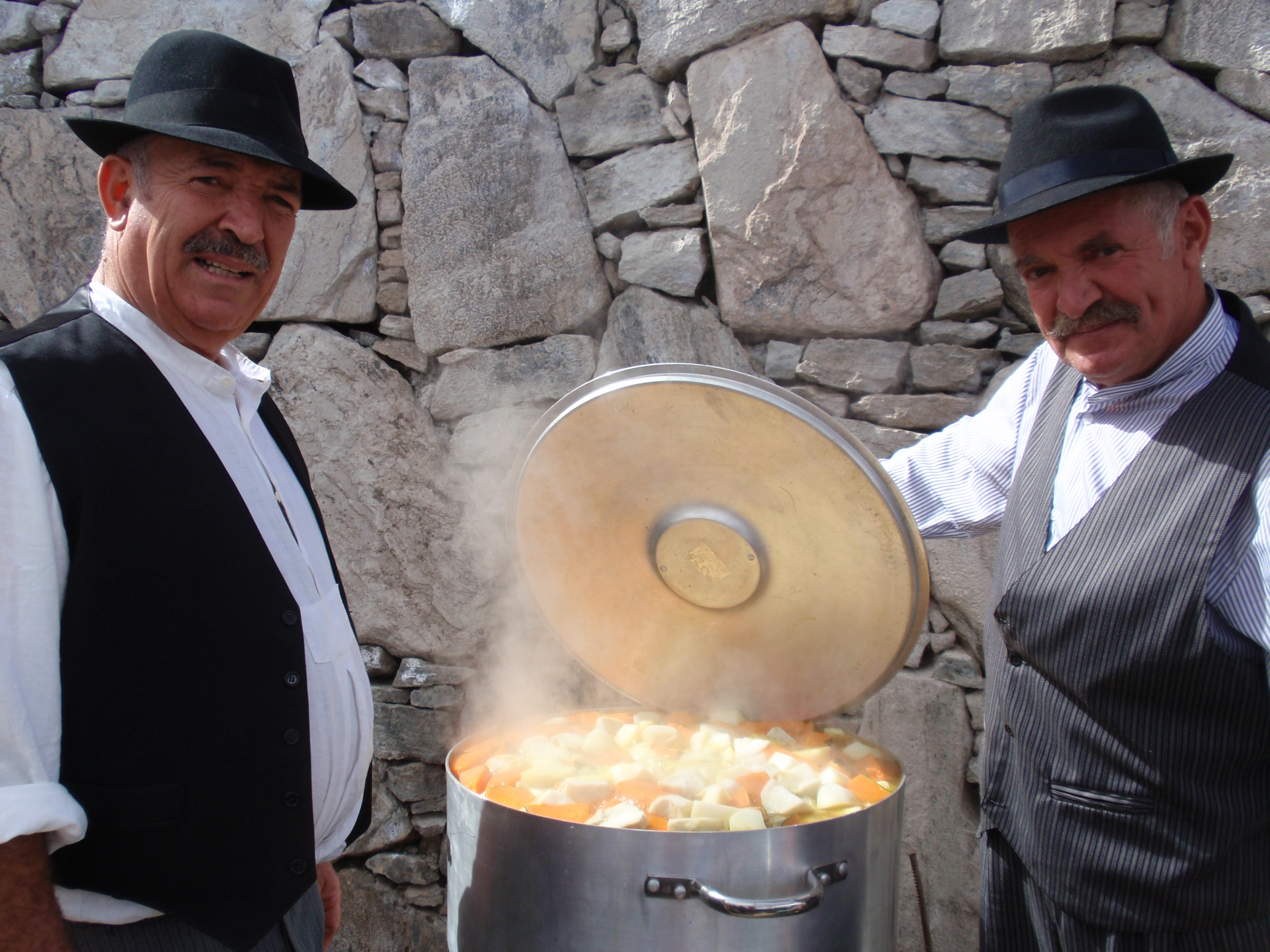 Local men display a traditional puchero canario, a hearty Canarian stew prepared in a large communal pot.