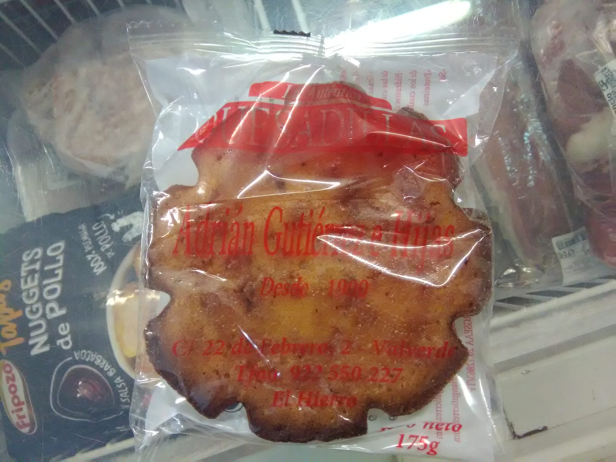 A traditional quesadilla herreña, a local pastry specialty, displayed in its packaging at a market or shop.